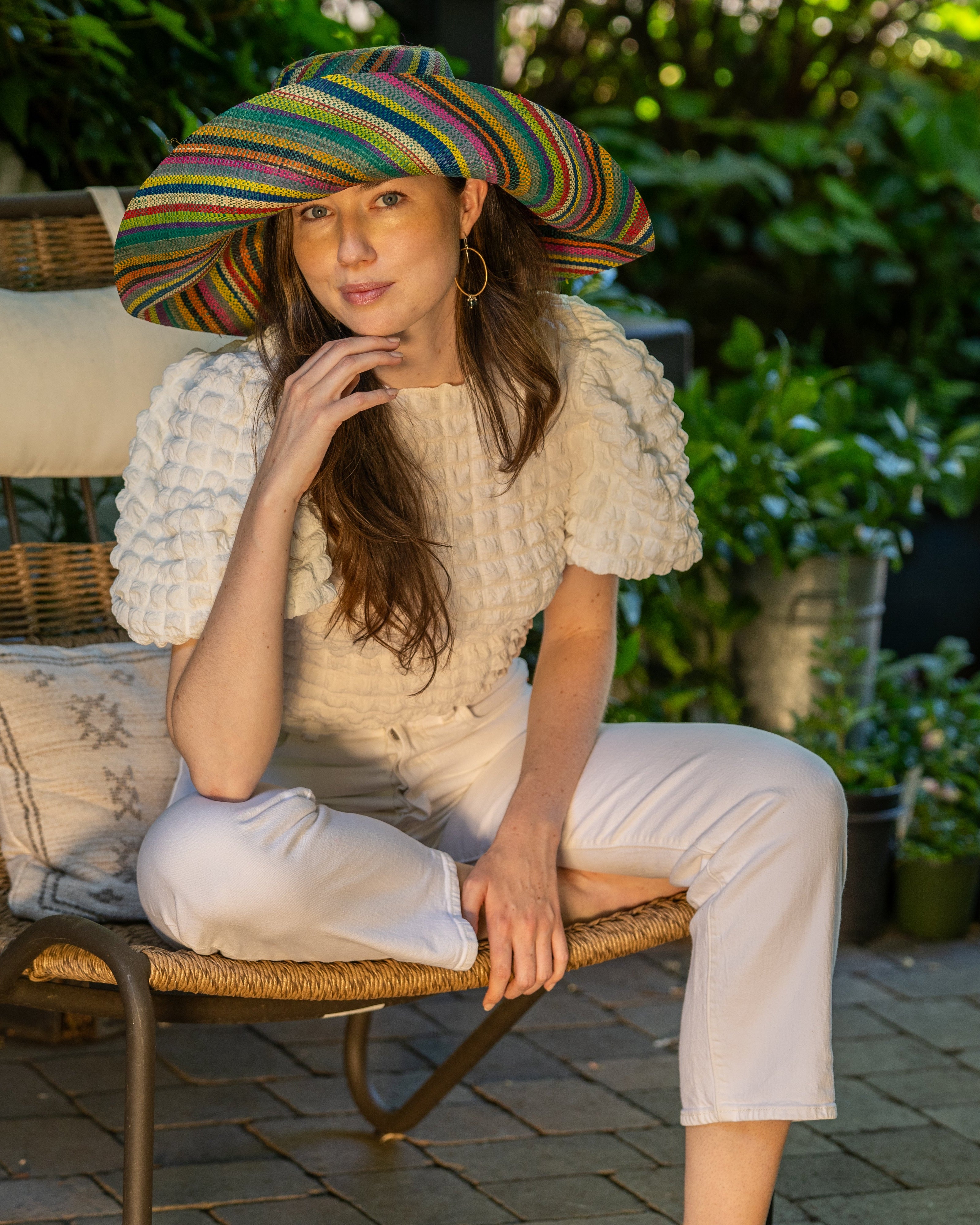 Model wearing Monica 7" Wide Brim Turquoise Stripes Multicolor Packable Straw Sun Hat Handmade loomed raffia in bands of natural, black, purple, yellow, orange, turquoise, grey, red, pink, and brown create a swirl pattern - Shebobo (with Tazi Turquoise Disc Straw Bucket Handbag)
