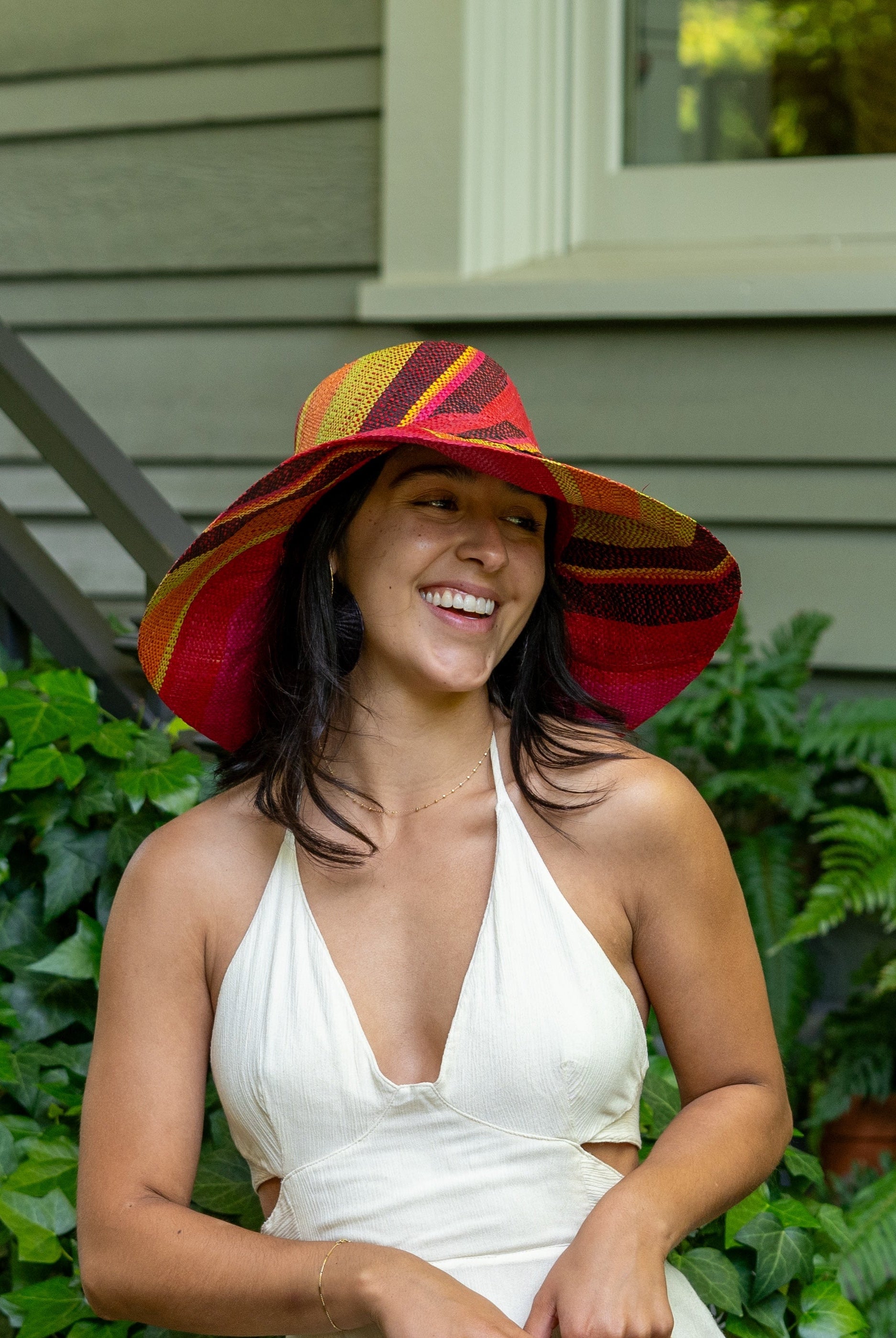 Model wearing Monica 5" Wide Brim Watermelon Swirl Multicolor Stripes Packable Straw Sun Hat Handmade loomed raffia in multi width bands of fuchsia pink, coral orange, red, yellow, black, lime green, etc. create a swirl pattern - Shebobo