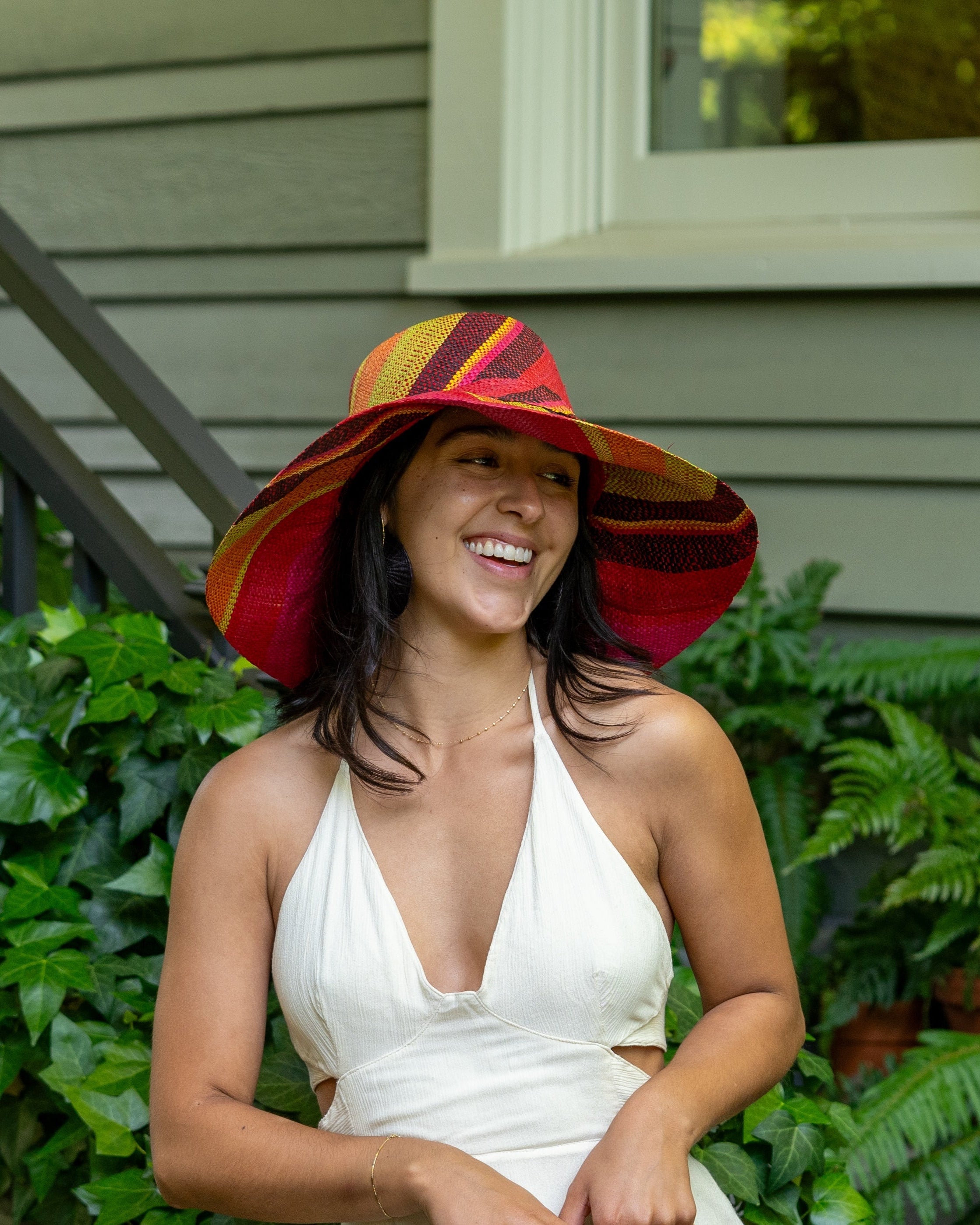 Model wearing Monica 5" Wide Brim Watermelon Swirl Multicolor Stripes Packable Straw Sun Hat Handmade loomed raffia in multi width bands of fuchsia pink, coral orange, red, yellow, black, lime green, etc. create a swirl pattern - Shebobo