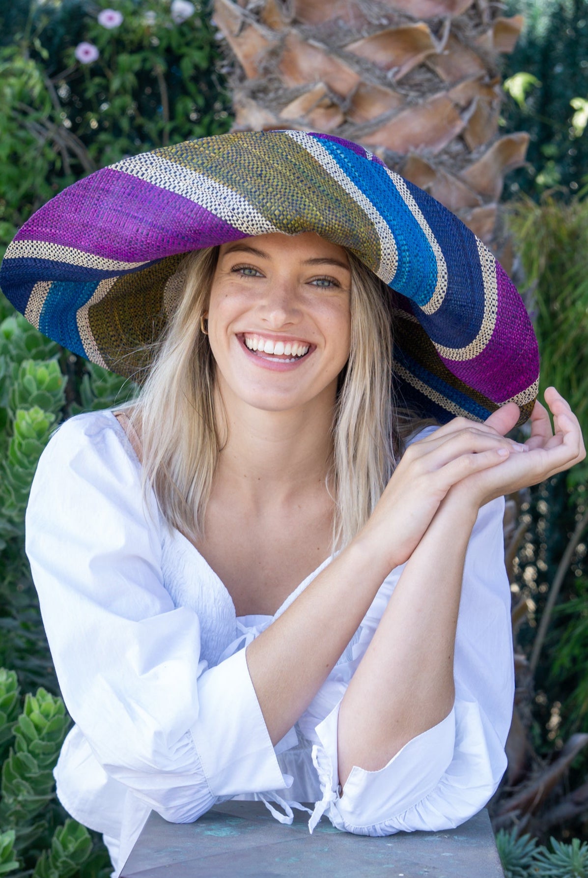 Model wearing Monica 7" Wide Brim Olive and Purple Swirl Multicolor Stripes Packable Straw Sun Hat Handmade loomed raffia multi width bands of turquoise blue, olive green, purple, and natural straw color create a swirl pattern - Shebobo
