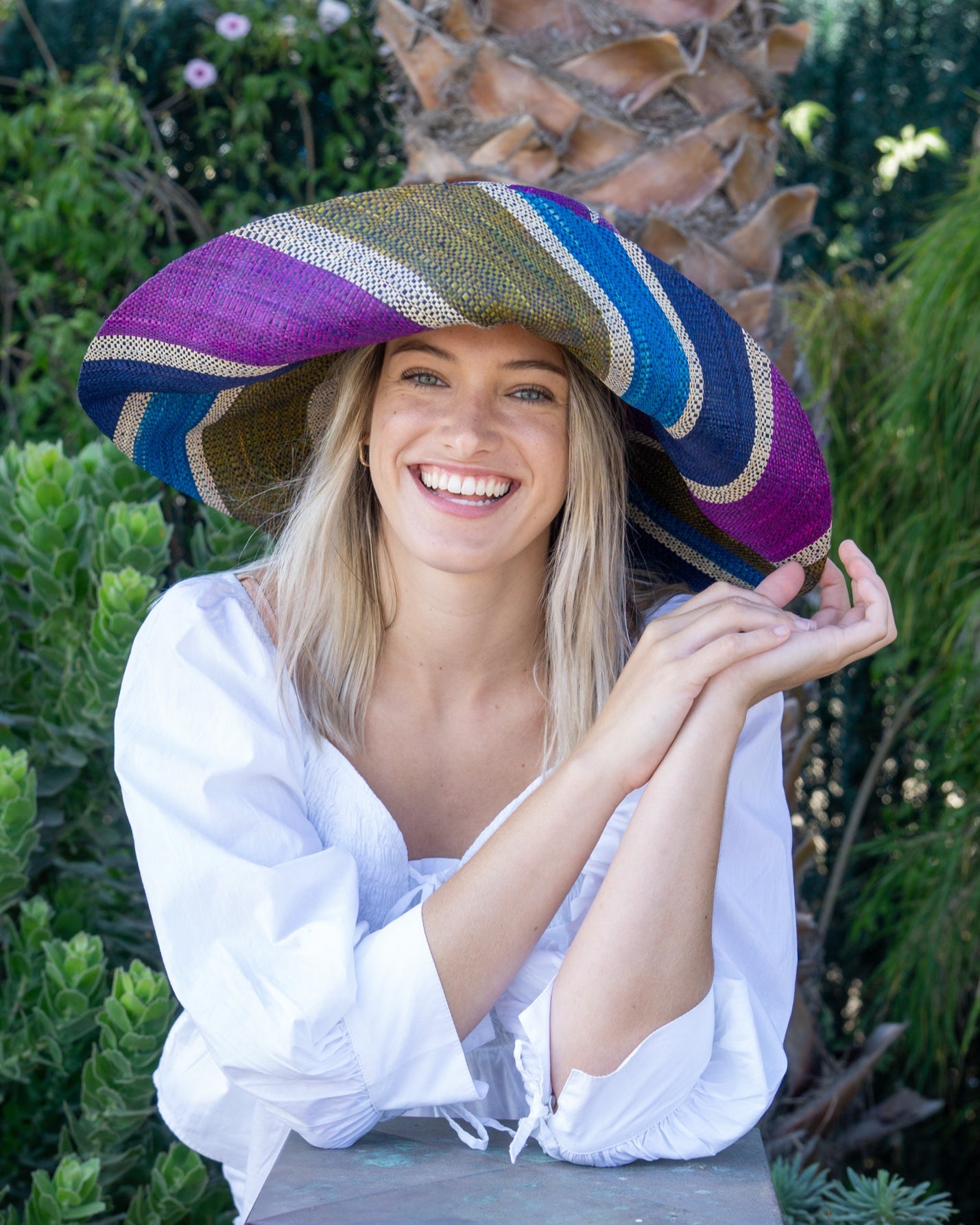 Model wearing Monica 7" Wide Brim Olive and Purple Swirl Multicolor Stripes Packable Straw Sun Hat Handmade loomed raffia multi width bands of turquoise blue, olive green, purple, and natural straw color create a swirl pattern - Shebobo