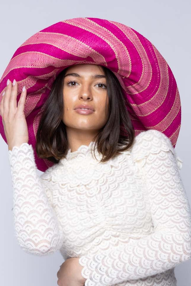 Model wearing Monica 5" & 7" Wide Brim Pink & Fuchsia Swirl Multicolor Stripes Packable Straw Sun Hat Handmade loomed raffia in multi width bands of light pink, fuchsia hot/bright/barbie/pink, natural straw color, etc. create a swirl pattern - Shebobo