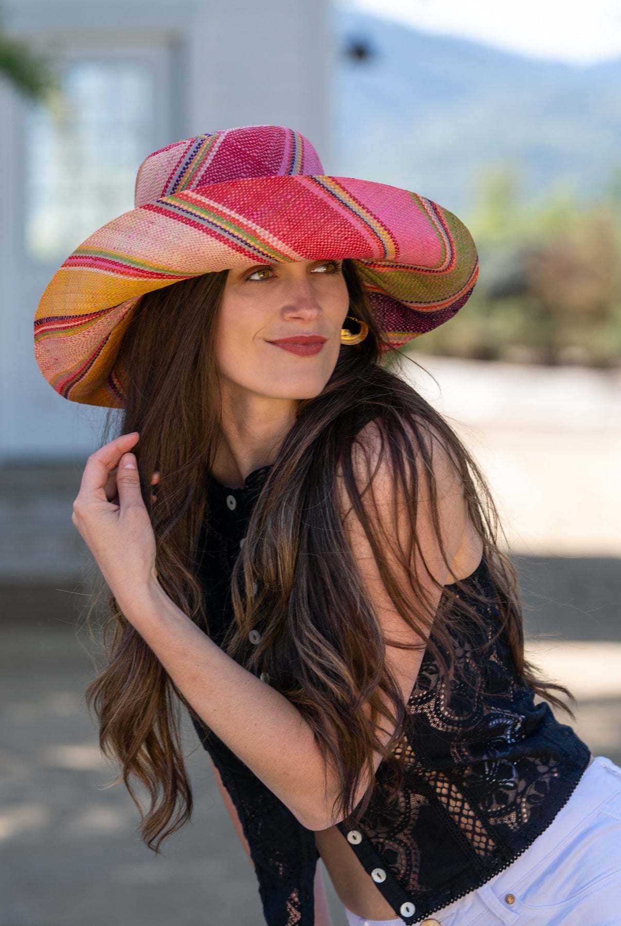 Model wearing Monica 5" Wide Brim Raspberry Swirl Multicolor Stripes Packable Straw Sun Hat Handmade loomed raffia in multi width bands of purple, light pink, coral orange/red, lime green, natural straw color, light blue, yellow, etc. create a swirl pattern - Shebobo