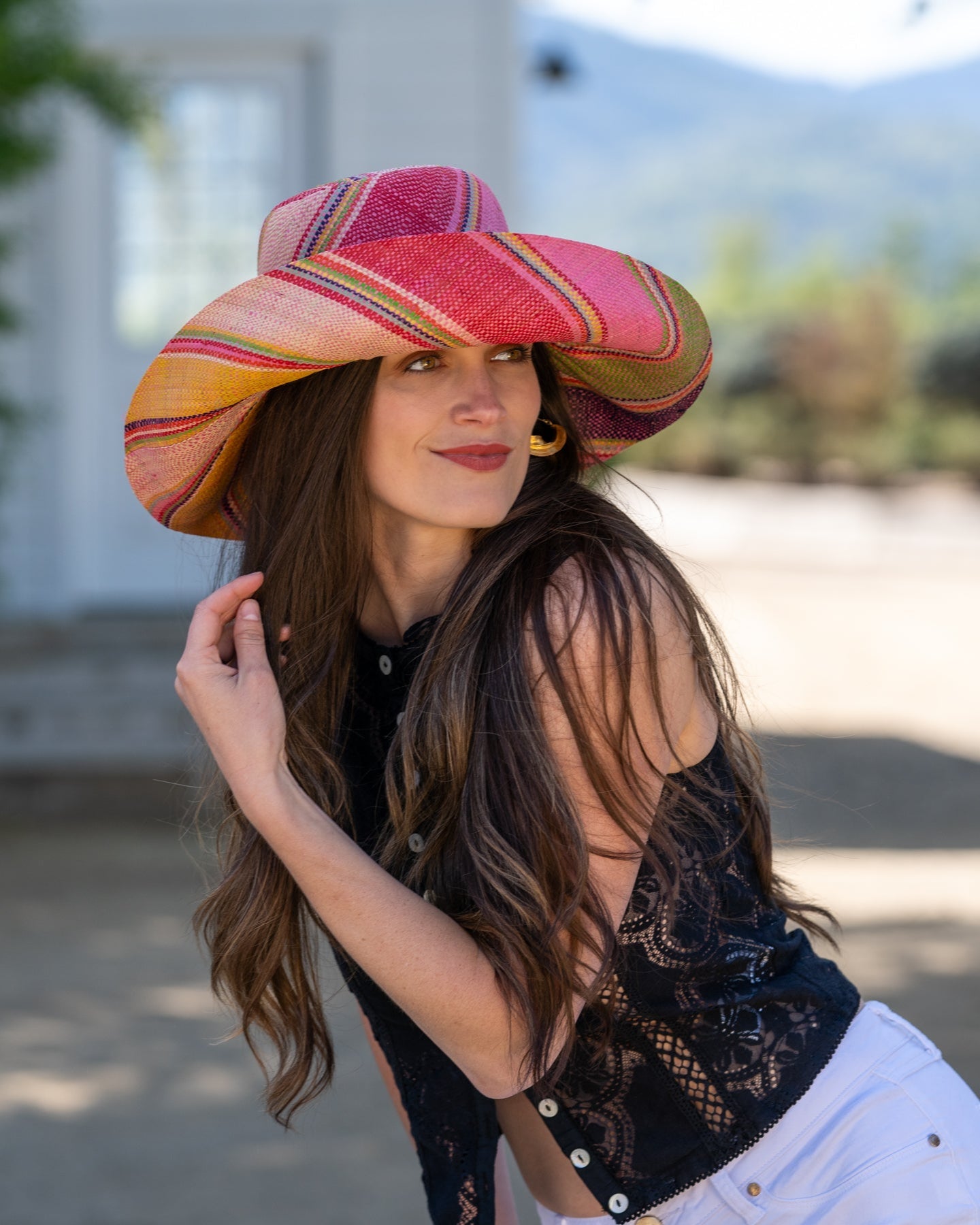 Model wearing Monica 5" Wide Brim Raspberry Swirl Multicolor Stripes Packable Straw Sun Hat Handmade loomed raffia in multi width bands of purple, light pink, coral orange/red, lime green, natural straw color, light blue, yellow, etc. create a swirl pattern - Shebobo
