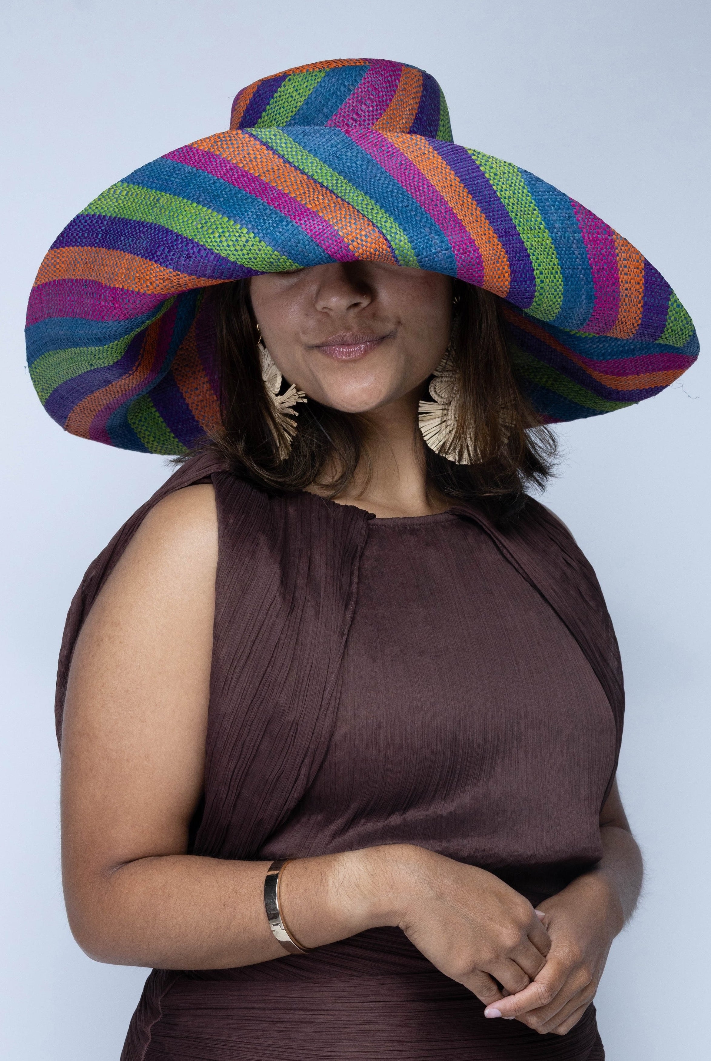 Model wearing Monica 7" Wide Brim Riviera Swirl Multicolor Stripes Packable Straw Sun Hat handmade loomed raffia in bands of fuchsia hot/bright/pink, purple, coral orange/red, midori lime/green, and turquoise blue stripes create a swirl pattern - Shebobo