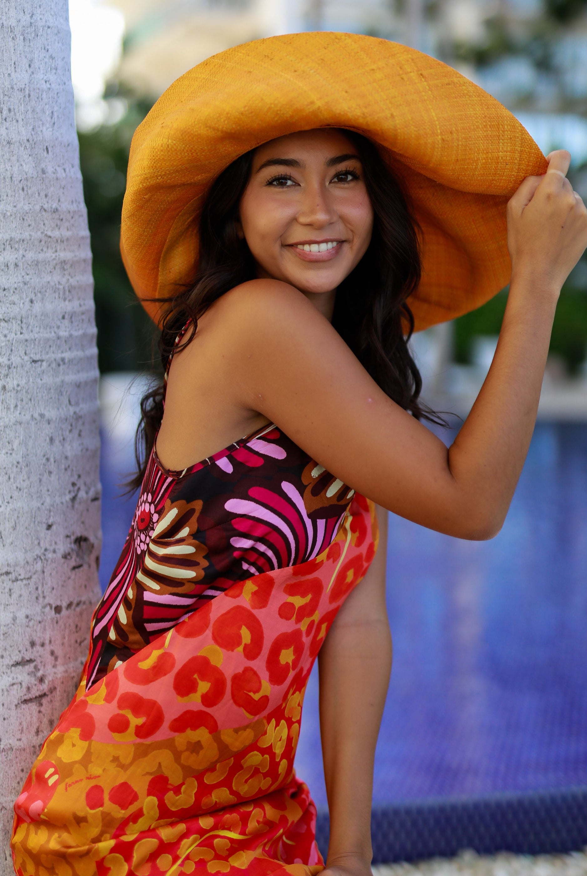 Model wearing Monica 7" Wide Brim Solid Color Packable Straw Sun Hat handmade loomed raffia in a solid hue of saffron yellow/orange - Shebobo
