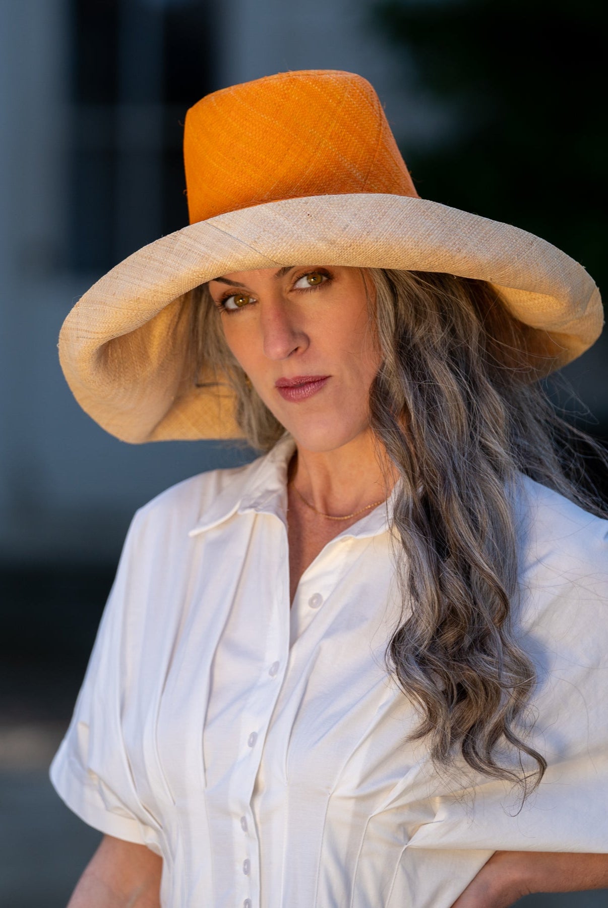 Model wearing Monica 7" Brim Two Tone Saffron Straw Hat handmade loomed raffia color block pattern of the top half saffron orange/yellow and the bottom half natural straw color - Shebobo