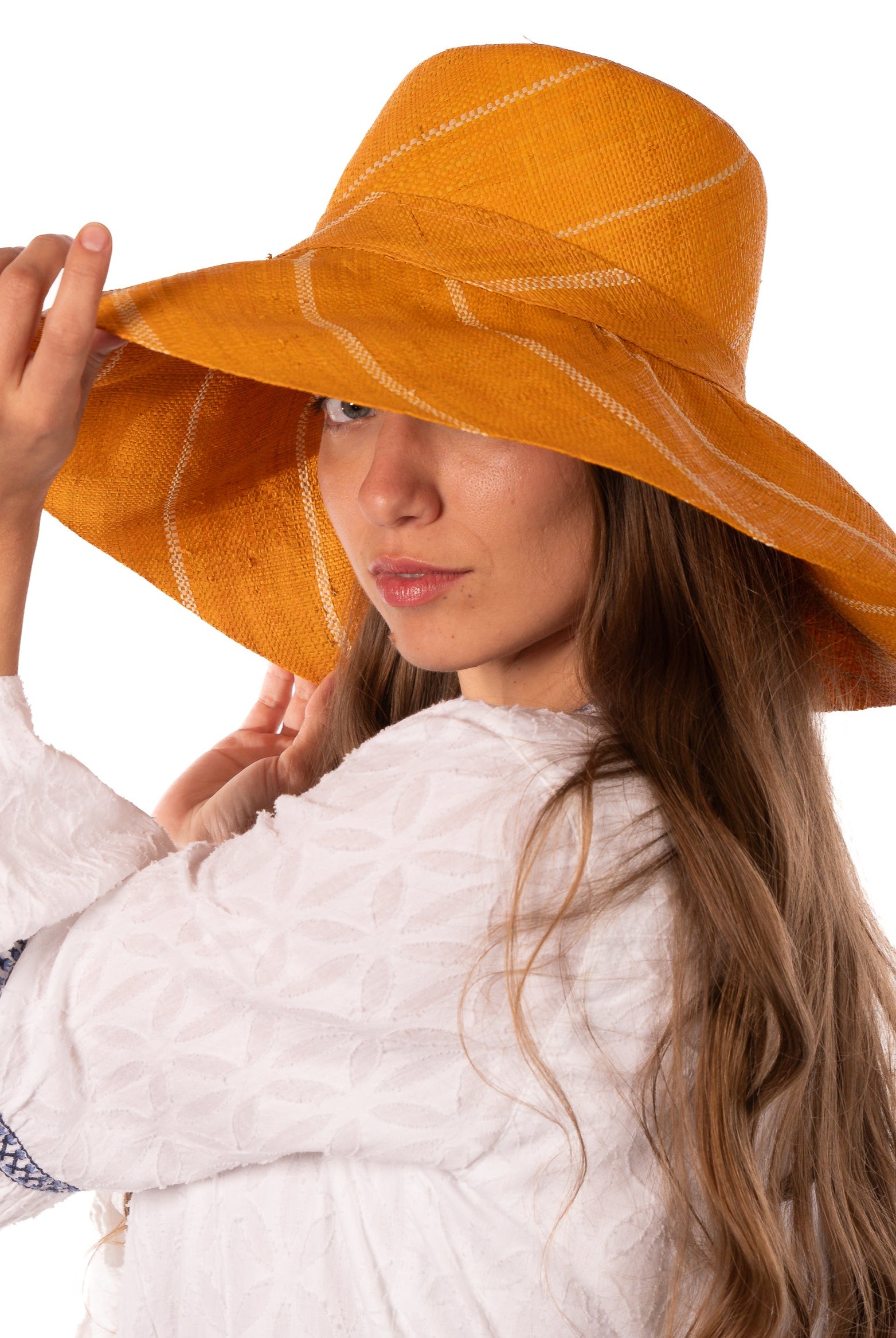 Model wearing Monica 5" Wide Brim Saffron Pinstripes Packable Straw Sun Hat handmade loomed raffia in wide stripes of saffron yellow/orange with narrow stripes of natural creating a swirl pattern - Shebobo