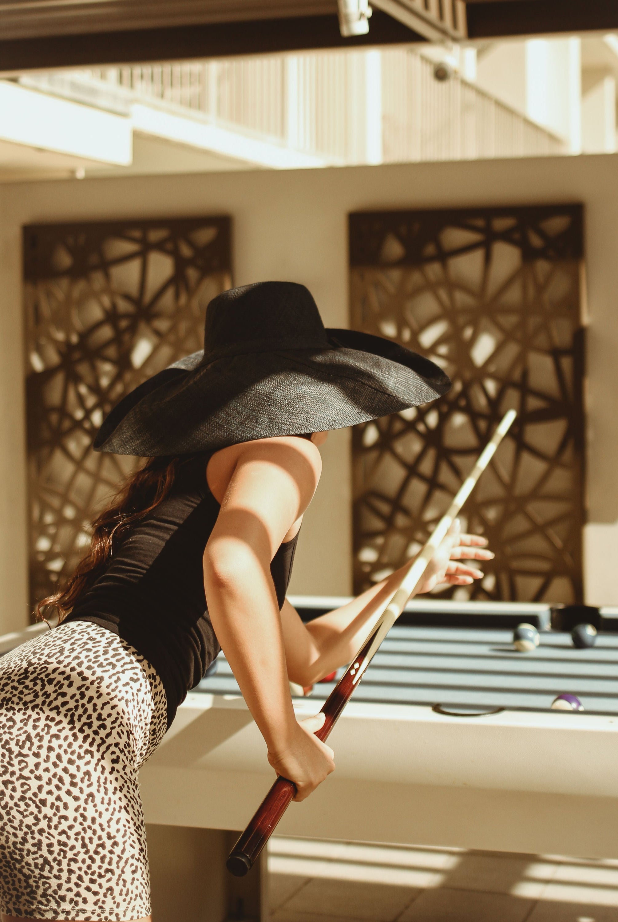 Model wearing Monica 7" Wide Brim Solid Color Packable Straw Sun Hat handmade loomed raffia in a solid hue of black - Shebobo