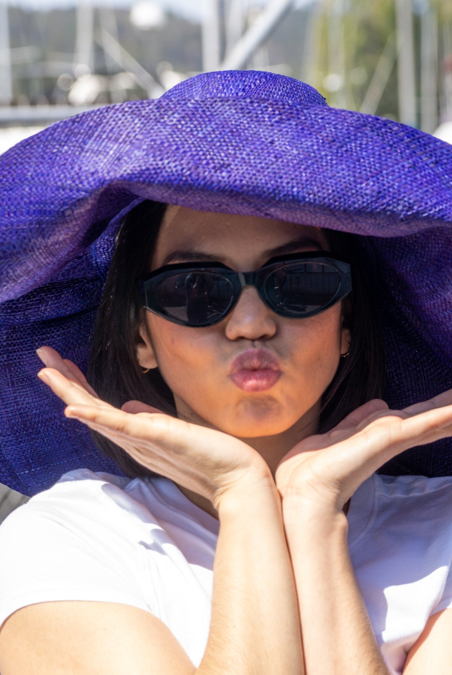 Model wearing Monica 7" Wide Brim Solid Color Packable Straw Sun Hat handmade loomed raffia in a solid hue of navy blue - Shebobo