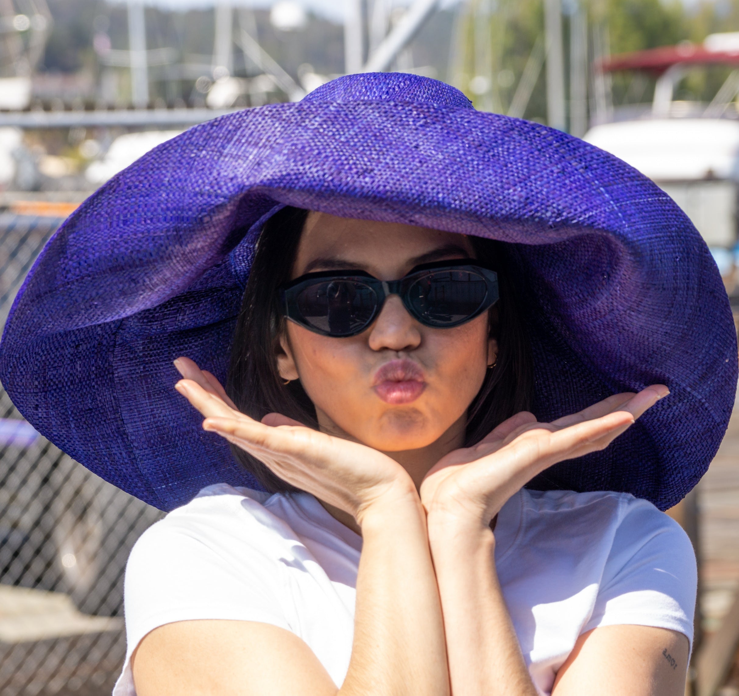Model wearing Monica 7" Wide Brim Solid Color Packable Straw Sun Hat handmade loomed raffia in a solid hue of navy blue - Shebobo