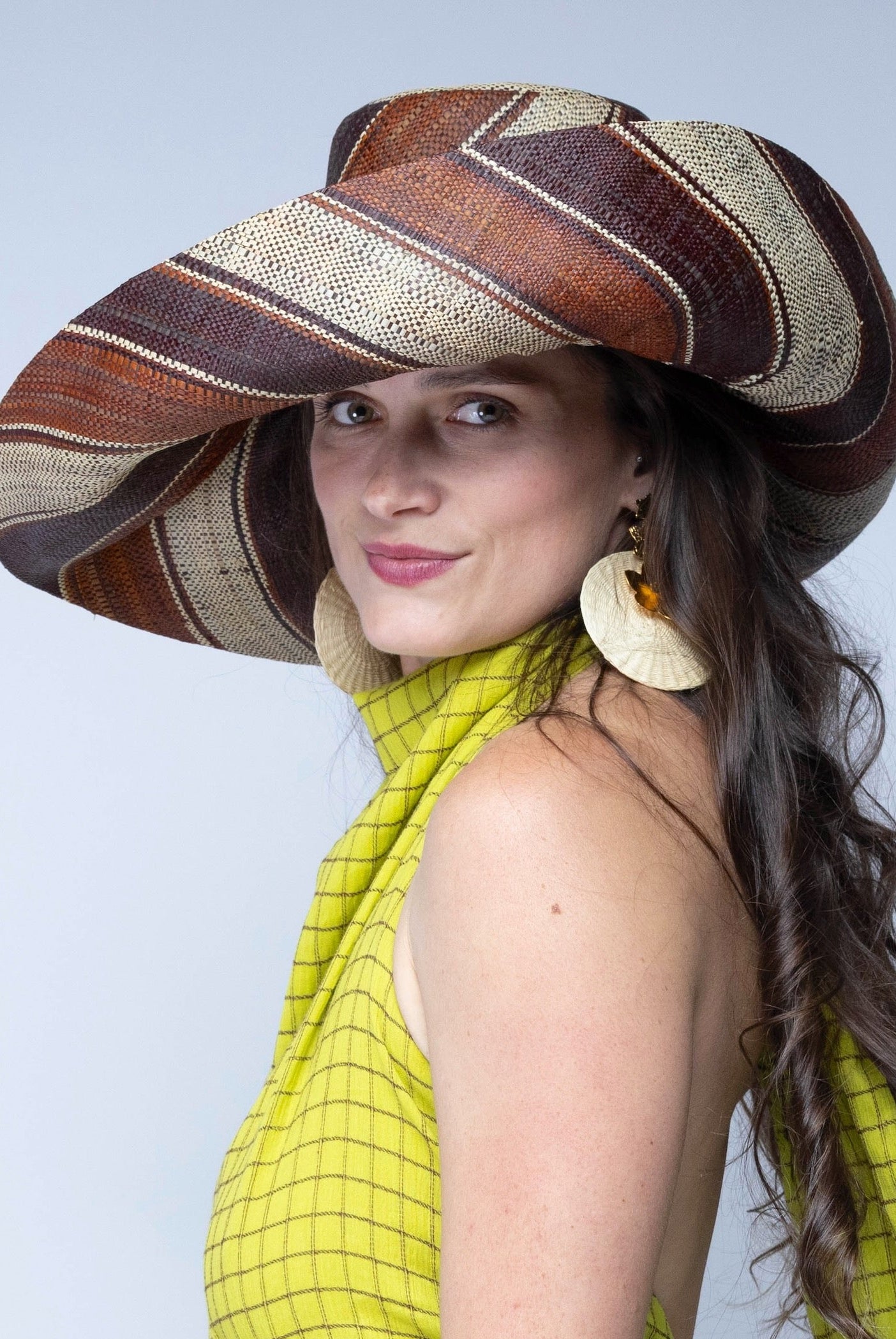 Model wearing Monica 7" Wide Brim Tawny Swirl Multicolor Stripes Packable Straw Sun Hat handmade loomed raffia in bands of natural straw color, mocha dark/chocolate/brown, and tobacco cinnamon/dark/brown stripes create a swirl pattern - Shebobo