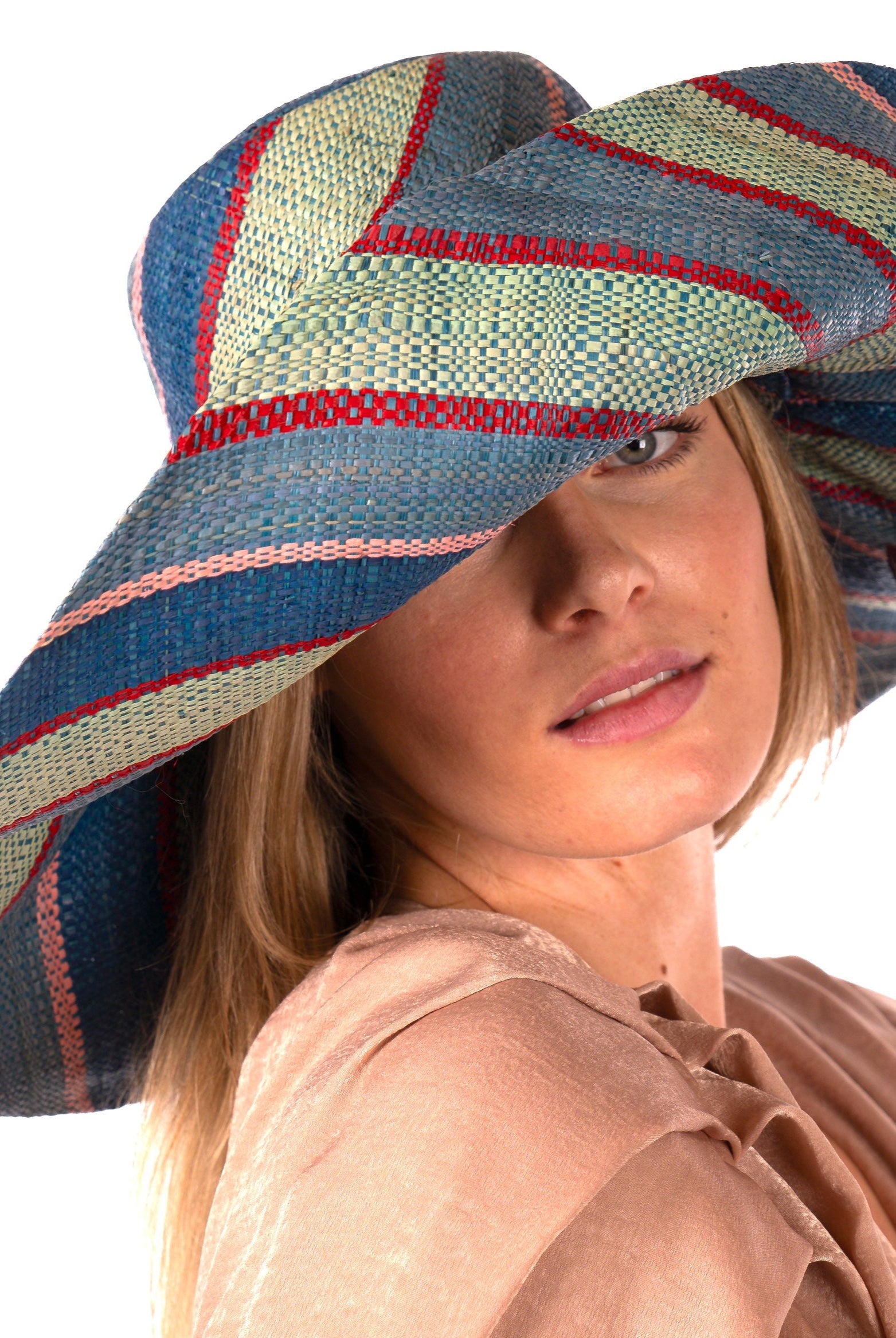 Model wearing Monica 7" Wide Brim Teal Swirl Multicolor Stripes Packable Straw Sun Hat Handmade loomed raffia in multi width bands of teal blue/green, seafoam green/blue, red, and pink create a swirl pattern - Shebobo