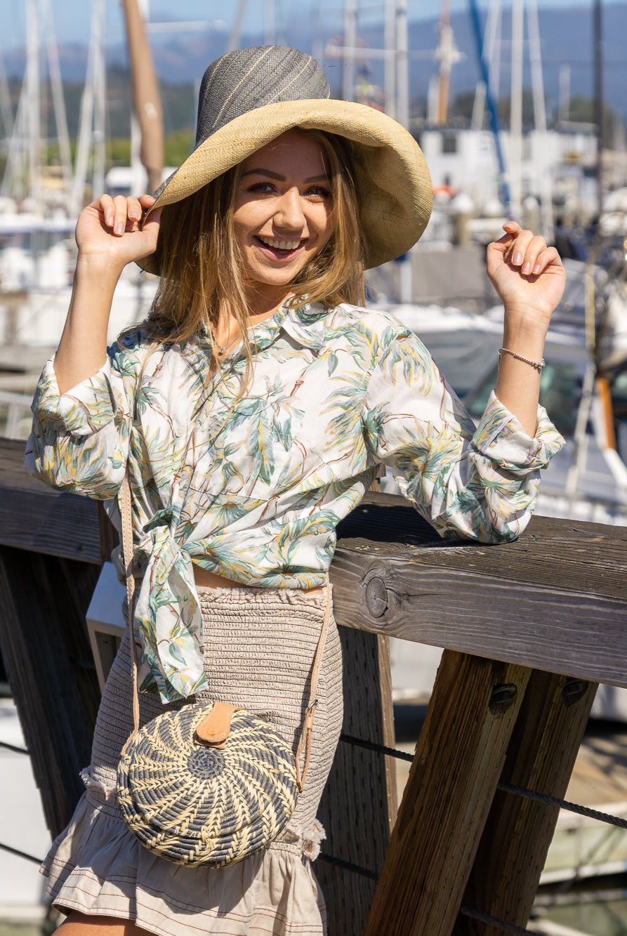 Model wearing Monica 5" Wide Brim Two Tone Grey Pinstripes Packable Straw Sun Hat handmade loomed raffia color block pattern with the top half wide bands of grey with narrow bands of natural straw color creating a pinstripe swirl and the bottom half natural straw color - Shebobo (with Clamshell Grey Two Tone Straw Crossbody Bag Purse)