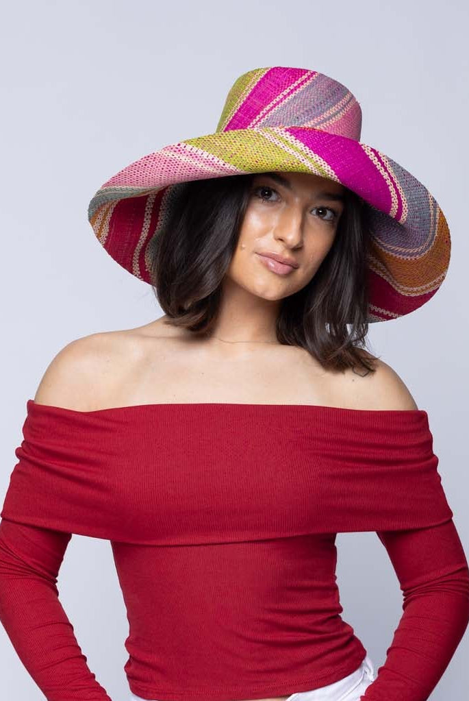 Model wearing 5" & 7" Wide Brim Zazzleberry Swirl Multicolor Stripes Packable Straw Sun Hat Handmade loomed raffia in multi width bands of fuchsia hot/bright/pink, light blue, light pink, red, orange, lime green, denim grey/blue, turquoise, and natural straw color create a swirl pattern - Shebobo