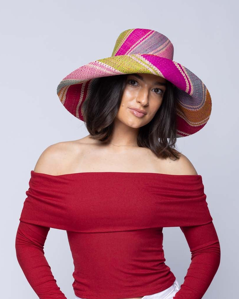Model wearing 5" & 7" Wide Brim Zazzleberry Swirl Multicolor Stripes Packable Straw Sun Hat Handmade loomed raffia in multi width bands of fuchsia hot/bright/pink, light blue, light pink, red, orange, lime green, denim grey/blue, turquoise, and natural straw color create a swirl pattern - Shebobo
