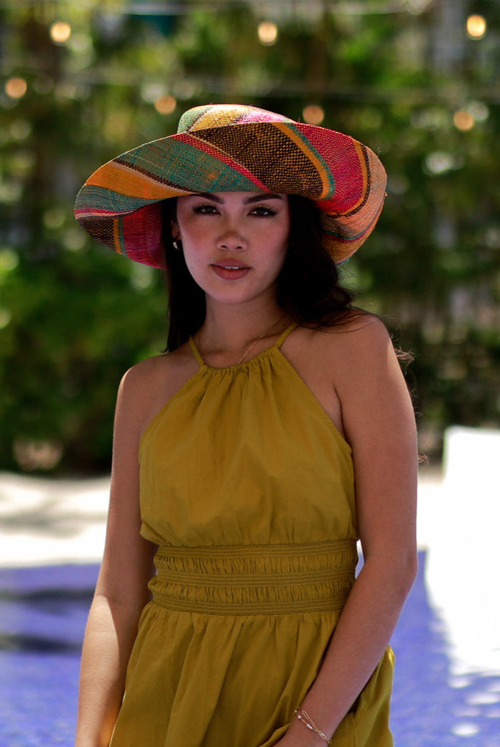 Model wearing Monica 5" Brim Carmalita Multicolor Stripes Packable Straw Sun Hat Handmade loomed raffia in multi width bands of saffron yellow, fuchsia pink, turquoise blue, black, and natural create a swirl pattern - Shebobo