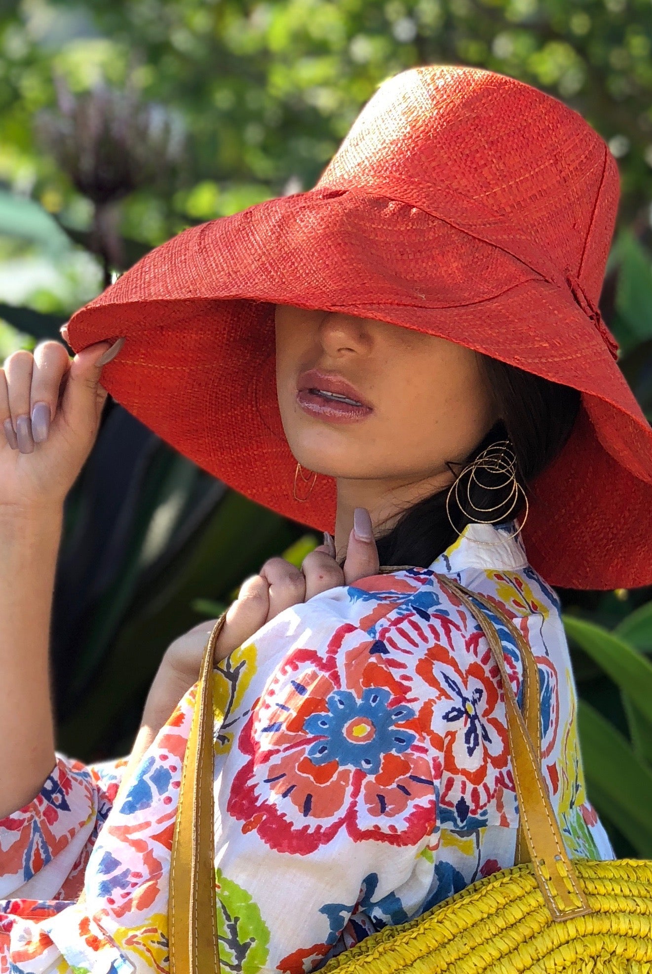 Model wearing Monica 5" Wide Brim Solid Color Packable Straw Sun Hat handmade loomed raffia in a solid hue of coral orange/red - Shebobo