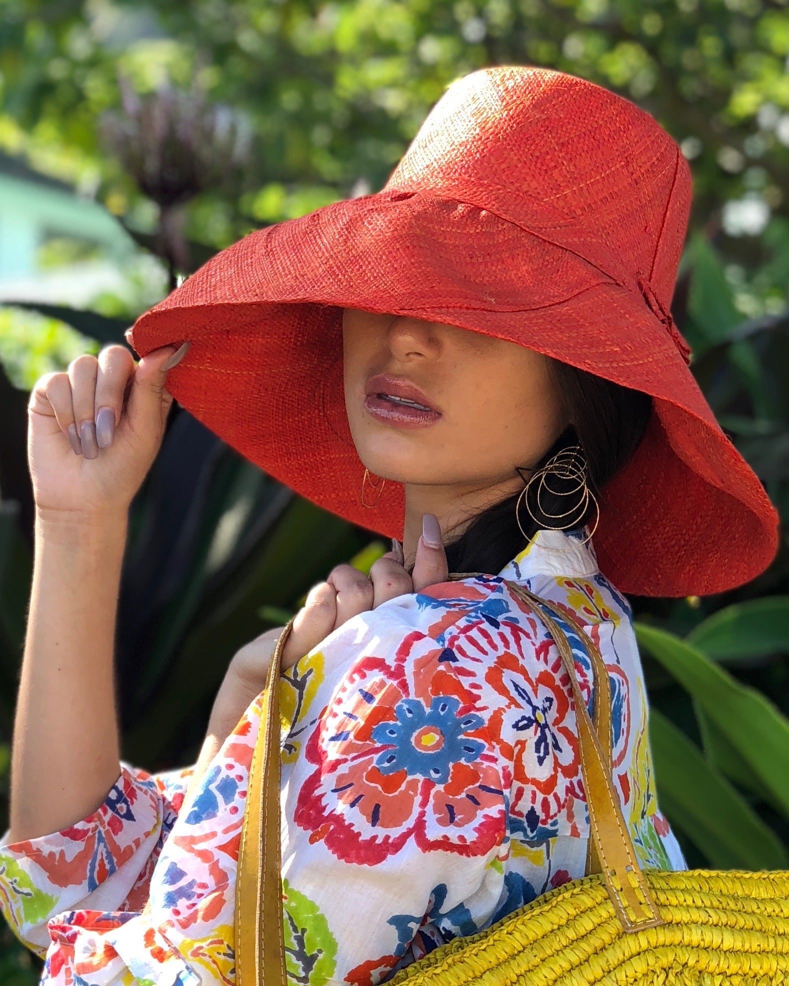 Model wearing Monica 5" Wide Brim Solid Color Packable Straw Sun Hat handmade loomed raffia in a solid hue of coral orange/red - Shebobo