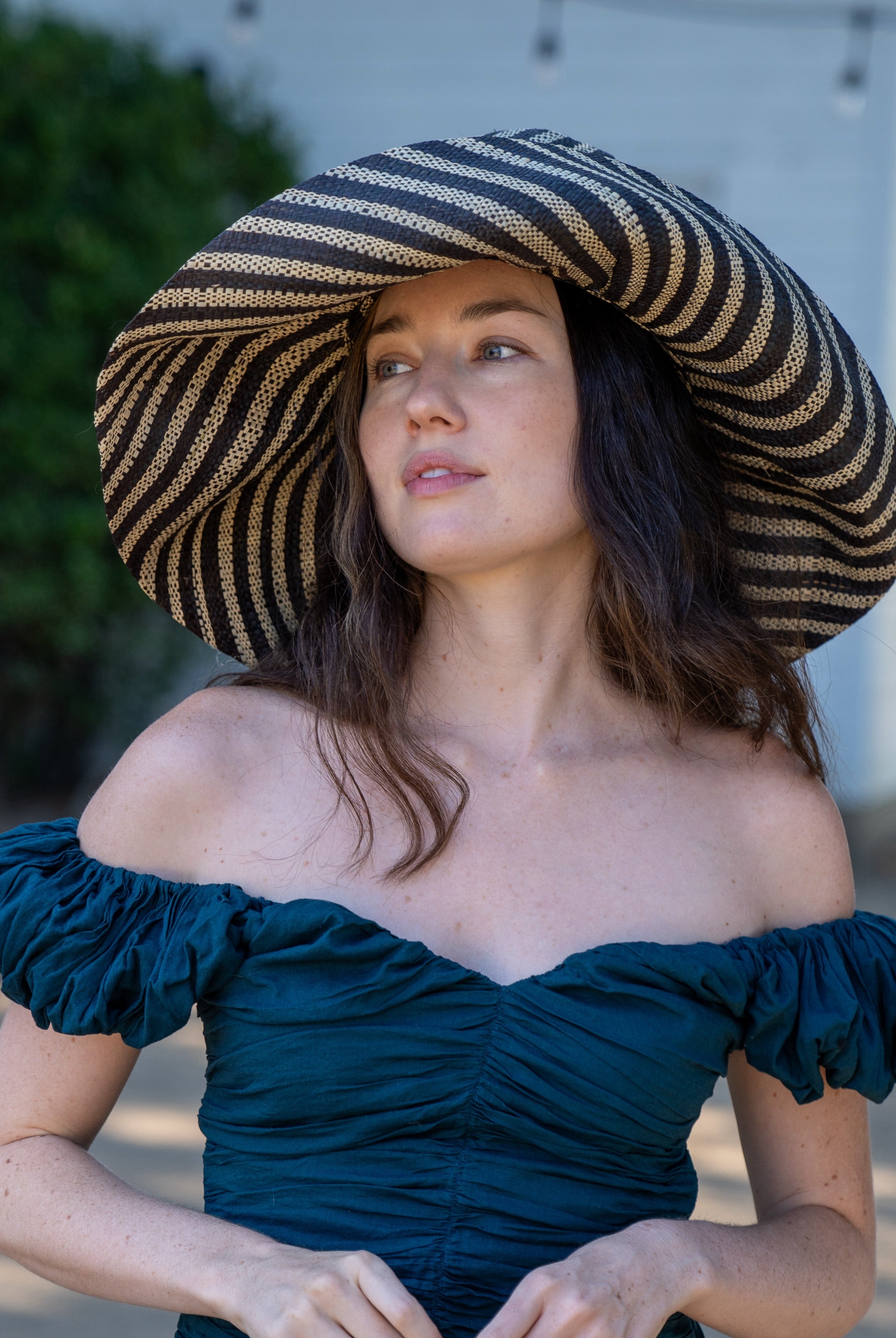 Model wearing Monica 7" Wide Brim Black and Natural Stripe Multicolor Stripe Pattern Packable Straw Sun Hat handmade loomed raffia in bands of black and natural straw color create a striped swirl pattern - Shebobo
