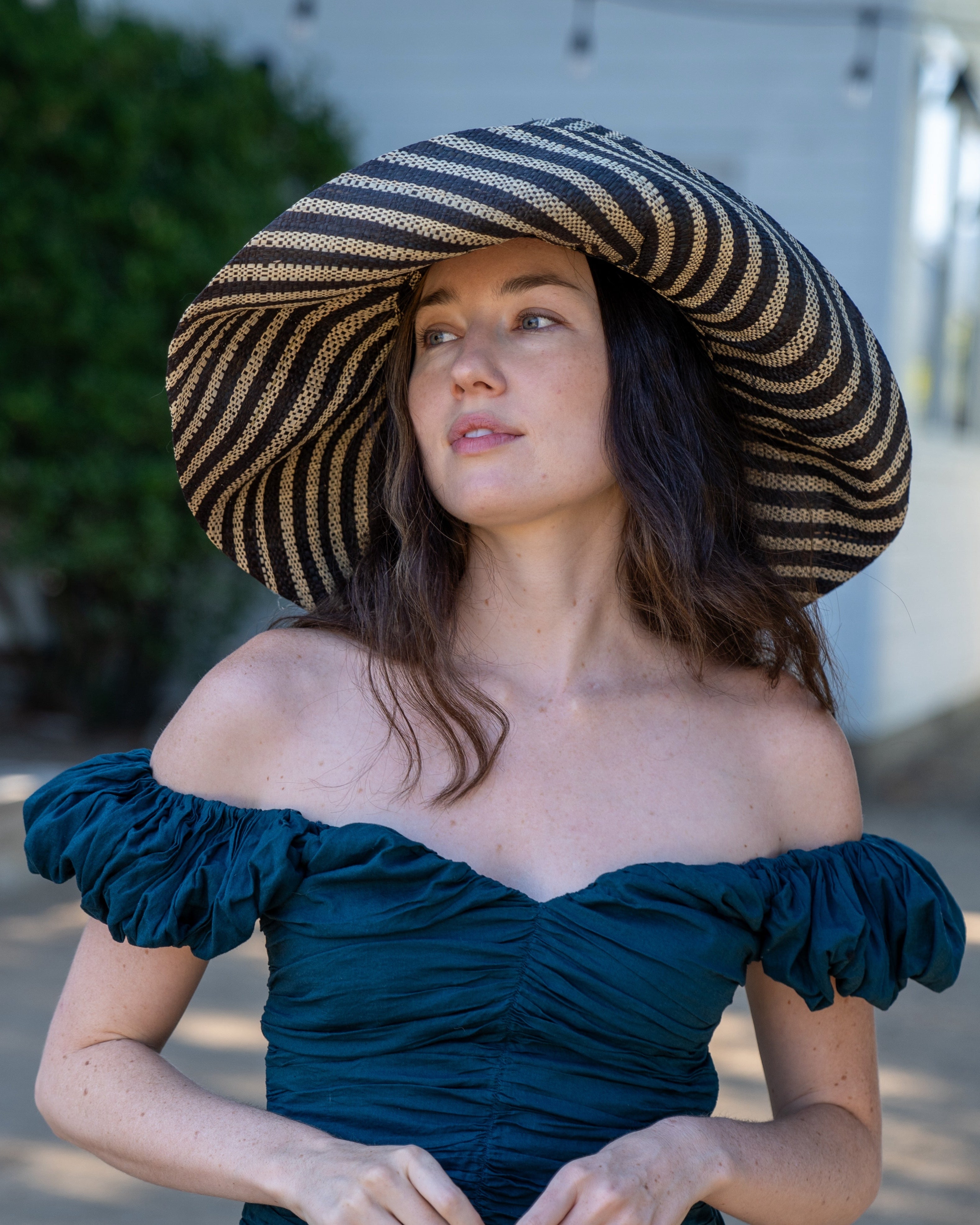 Model wearing Monica 7" Wide Brim Black and Natural Stripe Multicolor Stripe Pattern Packable Straw Sun Hat handmade loomed raffia in bands of black and natural straw color create a striped swirl pattern - Shebobo