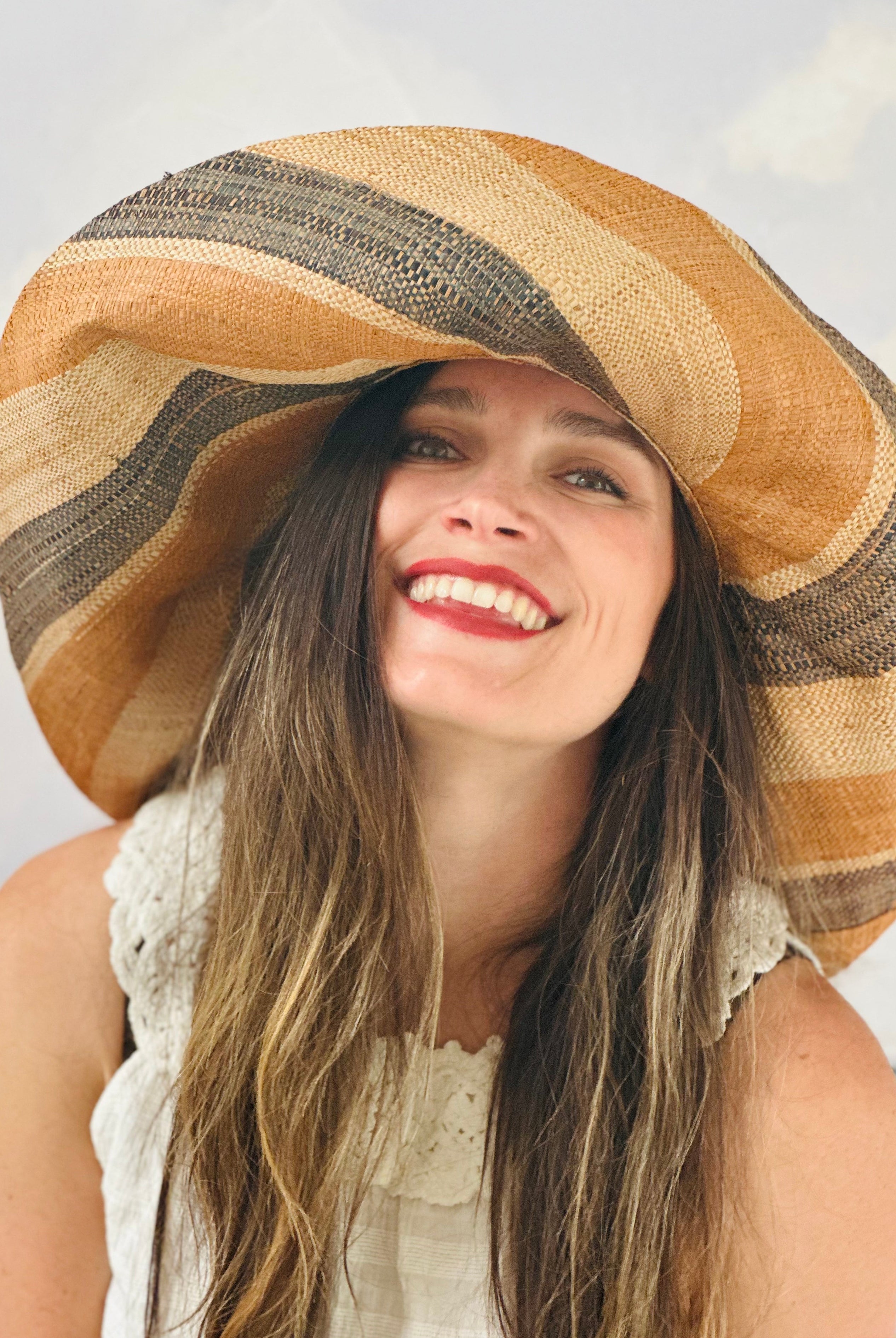 Model wearing Monica 7" Wide Brim Blush Swirl Multicolor Stripes Packable Straw Sun Hat Handmade loomed raffia in multi width bands of blush orange/pink, grey, and natural create a swirl pattern - Shebobo