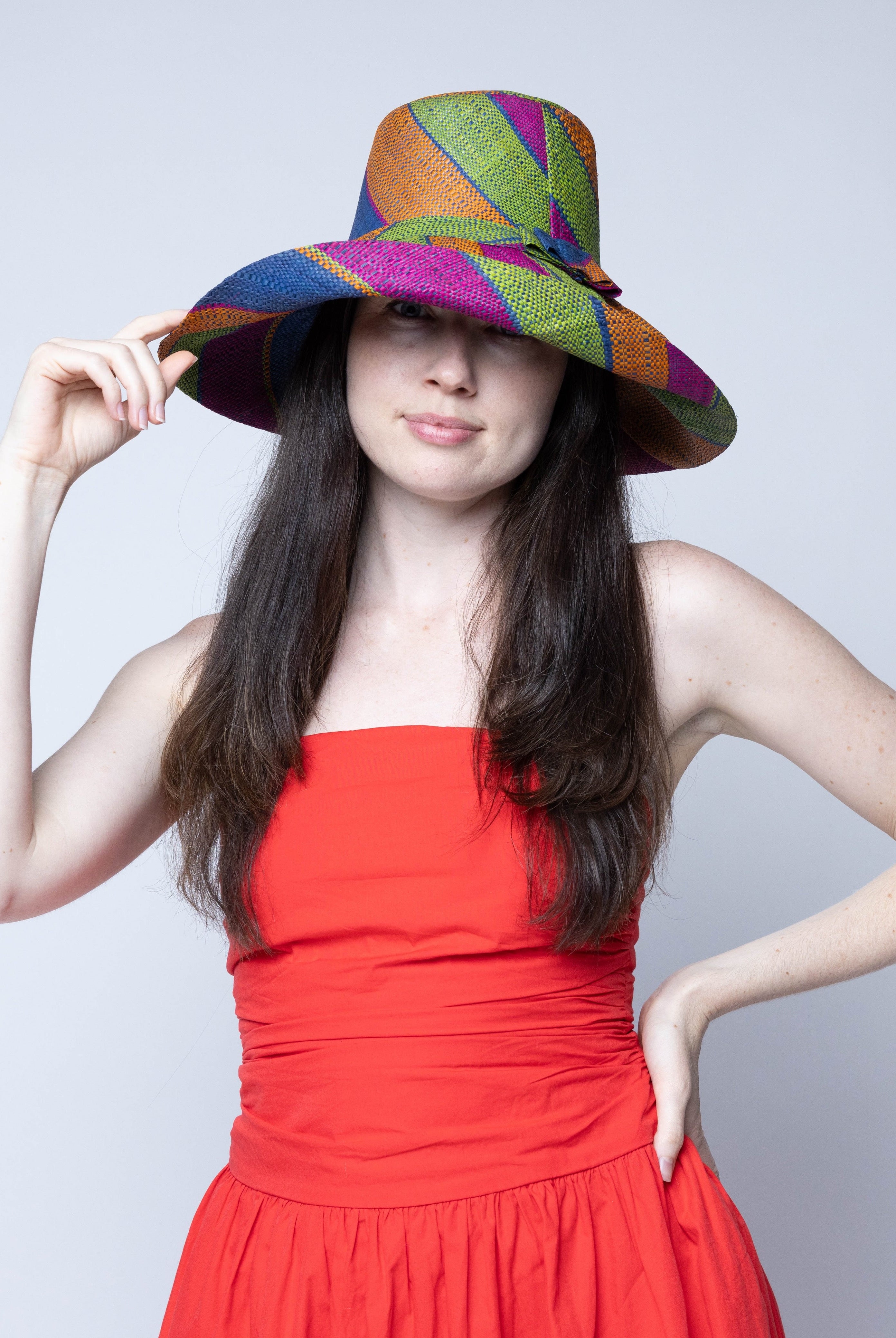 Model wearing Monica 5" Wide Brim Caribbean Swirl Multicolor Stripes Packable Straw Sun Hat Handmade loomed raffia in multi width bands of fuchsia pink, orange, dusk navy/dark/blue, and lime green create a swirl pattern - Shebobo