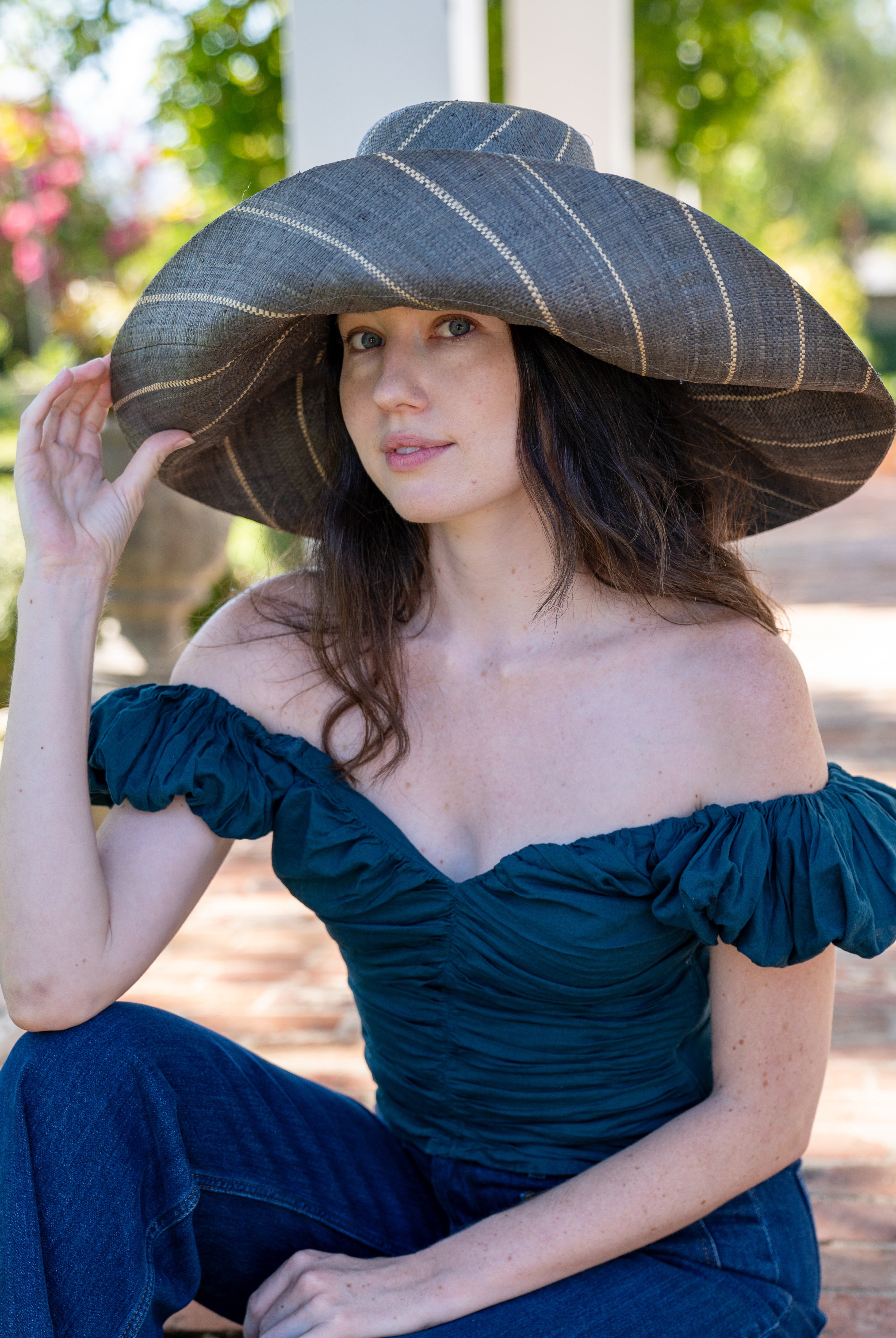 Model wearing Monica 7" Wide Brim Grey Pinstripes Packable Straw Sun Hat handmade loomed raffia in wide bands of grey with narrow bands of natural straw color create a striped swirl pattern - Shebobo