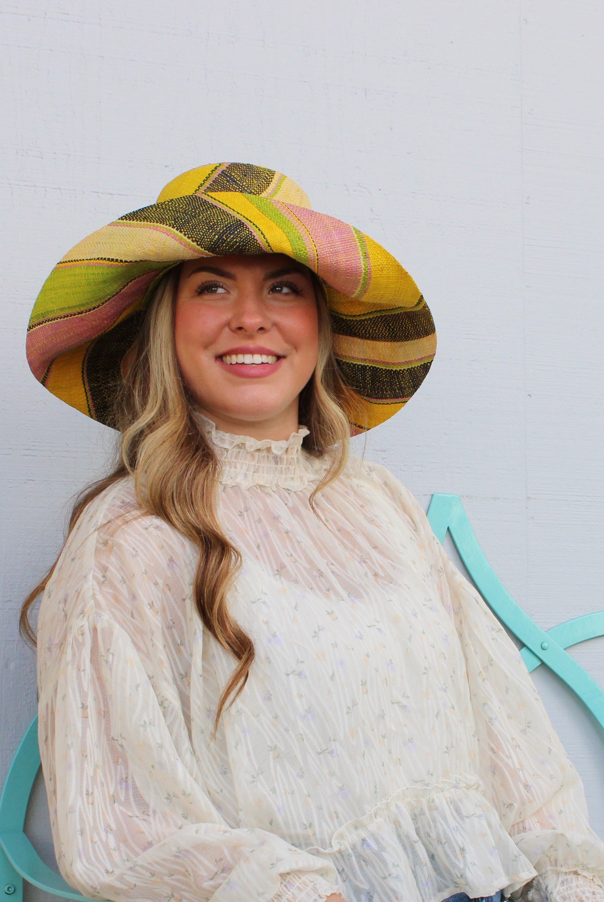 Model wearing Monica 5" Wide Brim Lemonade Swirl Multicolor Stripes Packable Straw Sun Hat Handmade loomed raffia in multi width bands of yellow, wisteria light/purple/pink, midori lime/green, black, natural straw color etc. create a swirl pattern - Shebobo