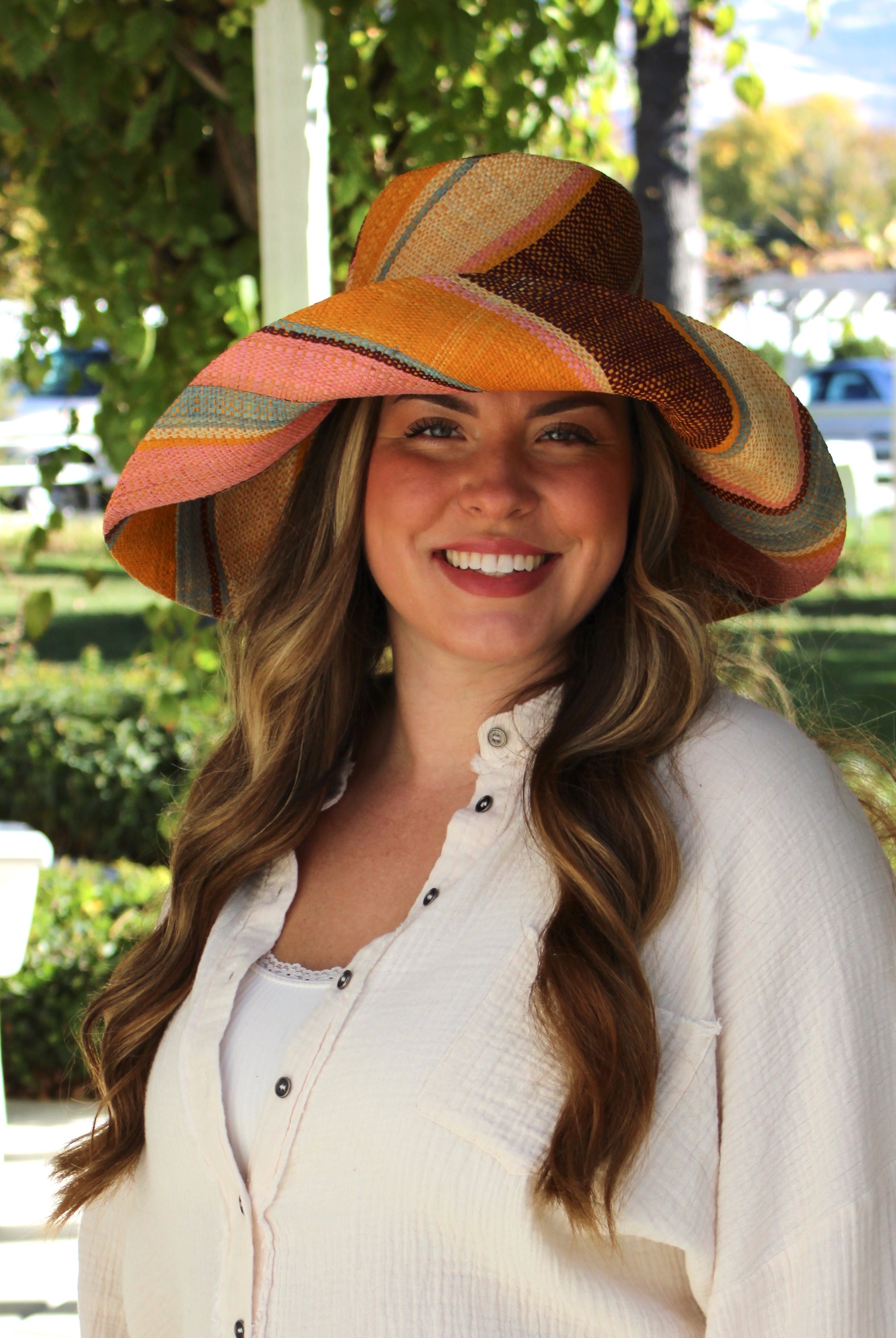 Model wearing Monica 5" Wide Brim Pink Blue Swirl Multicolor Stripes Packable Straw Sun Hat Handmade loomed raffia in multi width bands of saffron yellow, light pink, light blue, black, natural straw color etc. create a swirl pattern - Shebobo
