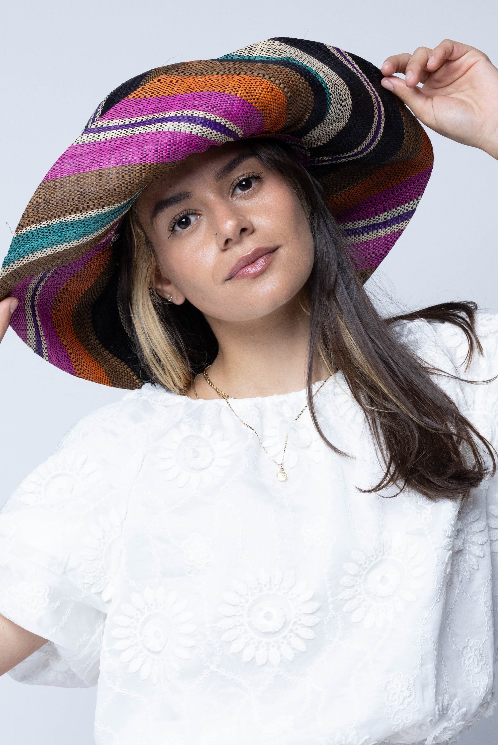 Model wearing Monica 5" Wide Brim Revel Swirl Multicolor Stripes Packable Straw Sun Hat Handmade loomed raffia in multi width bands of coral orange, fuchsia pink, teal blue/green, purple, cinnamon/tobacco/brown, black, natural straw color etc. create a swirl pattern - Shebobo