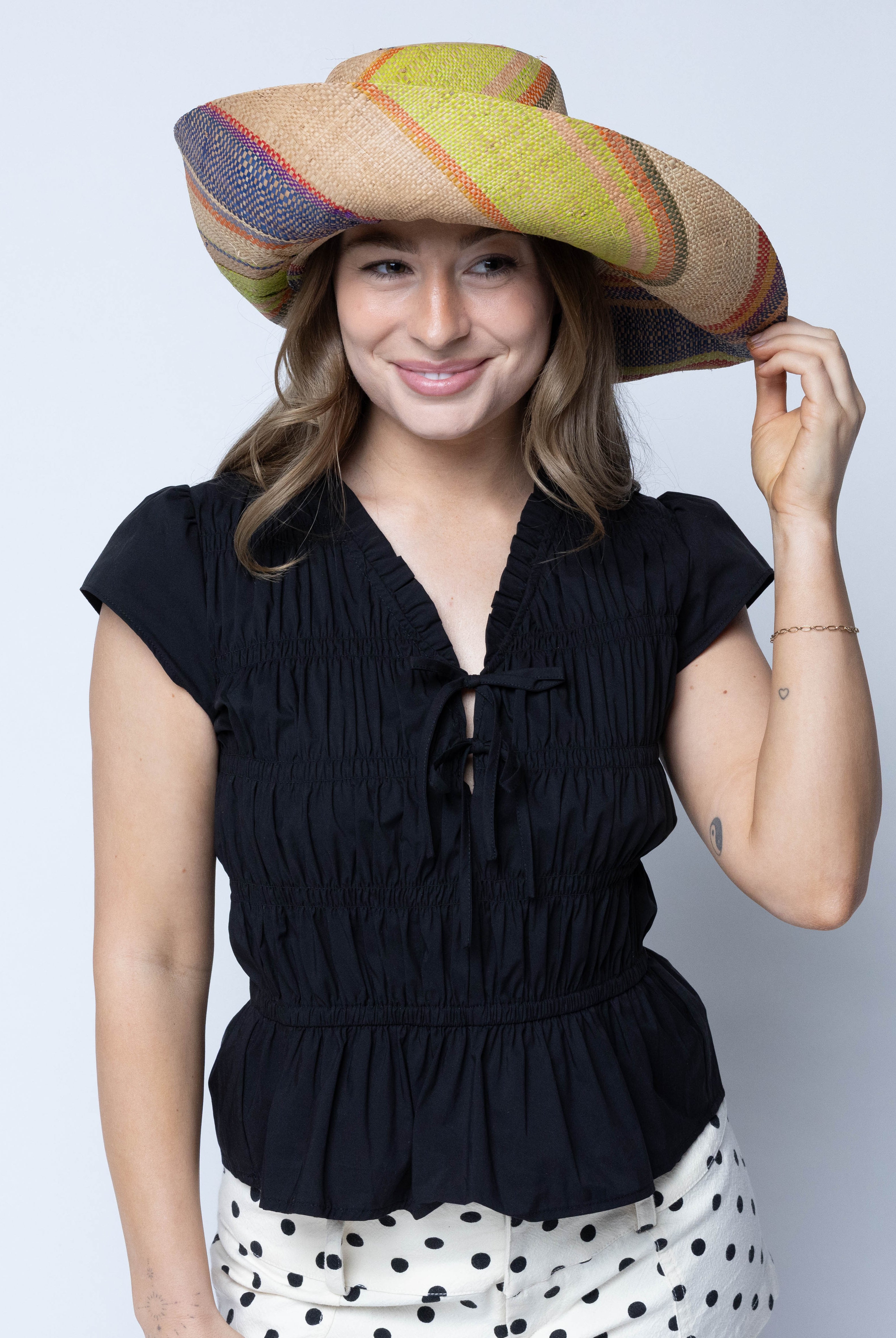 Model wearing Monica 5" Wide Brim Rio Swirl Multicolor Stripes Packable Straw Sun Hat Handmade loomed raffia in multi width bands of cappuccino light brown, lime green, saffron yellow, red, purple, navy blue, natural straw color, etc. create a swirl pattern - Shebobo