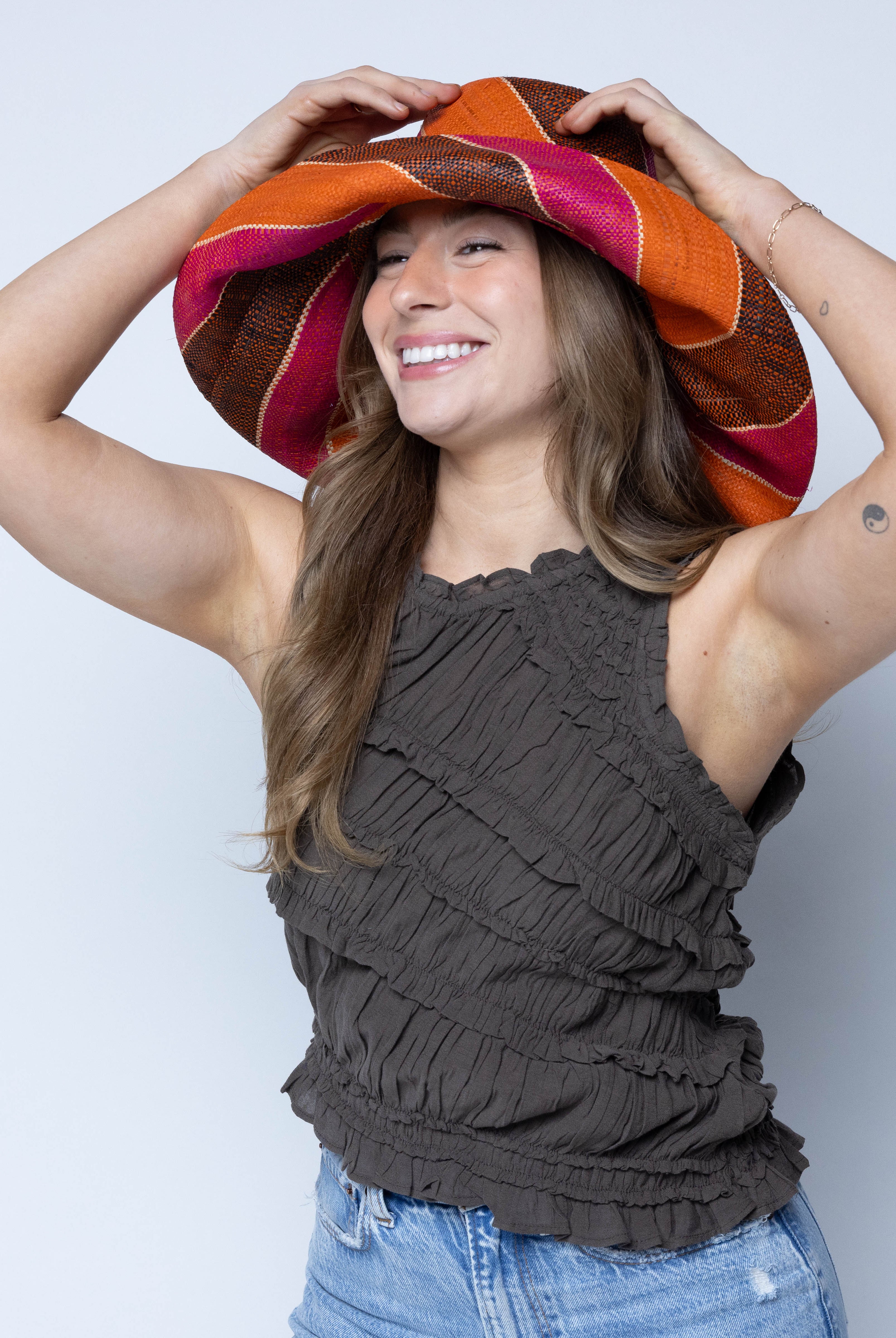Model wearing Monica 5" Wide Brim Whimsy Swirl Multicolor Stripes Packable Straw Sun Hat Handmade loomed raffia in multi width bands of coral orange, fuchsia pink, black, natural straw color, etc. create a swirl pattern - Shebobo