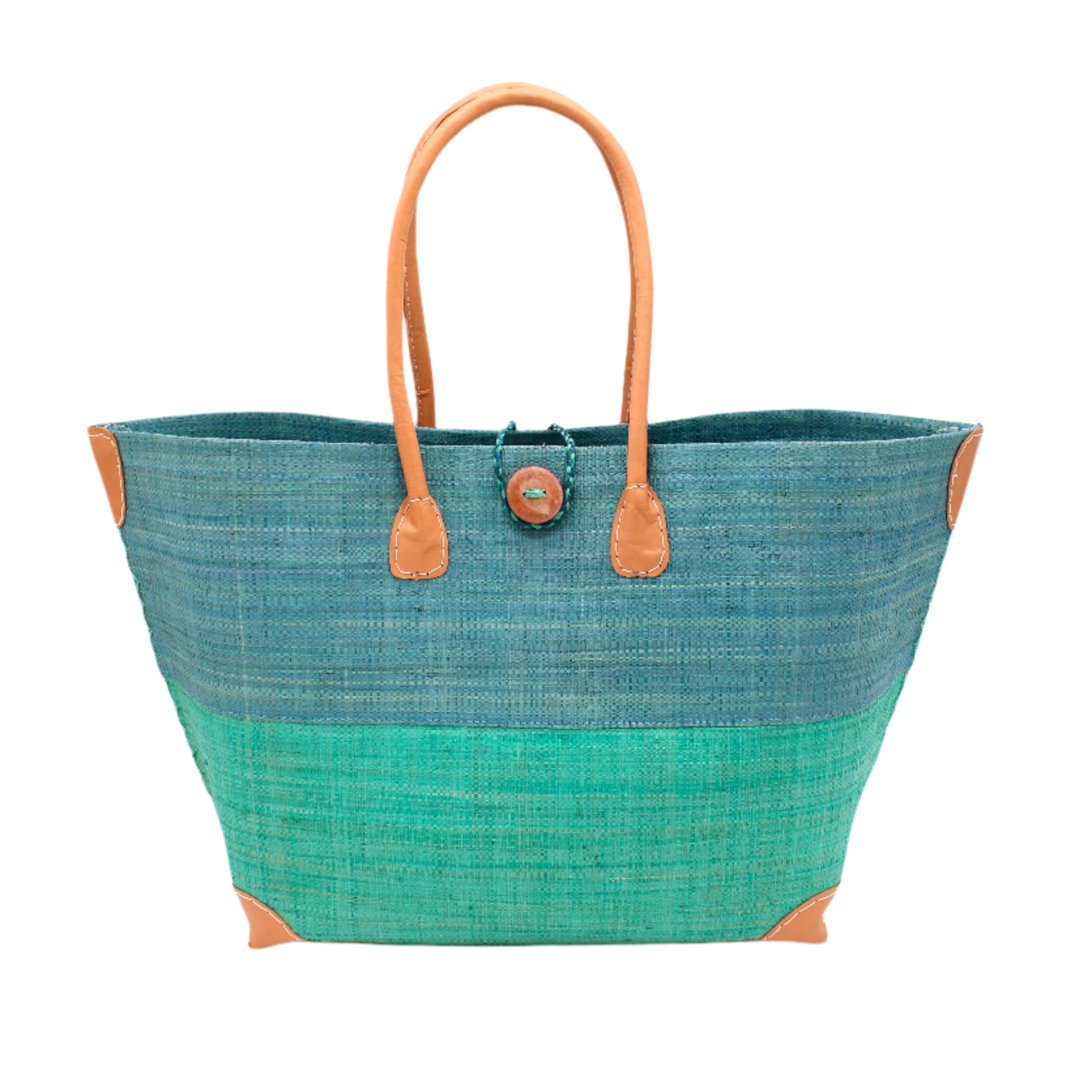 Model wearing Monterey Two Tone Straw Tote Bag handmade loomed raffia fibers in a color block pattern of turquoise blue colored upper half, and seafoam blue/green lower half - Shebobo