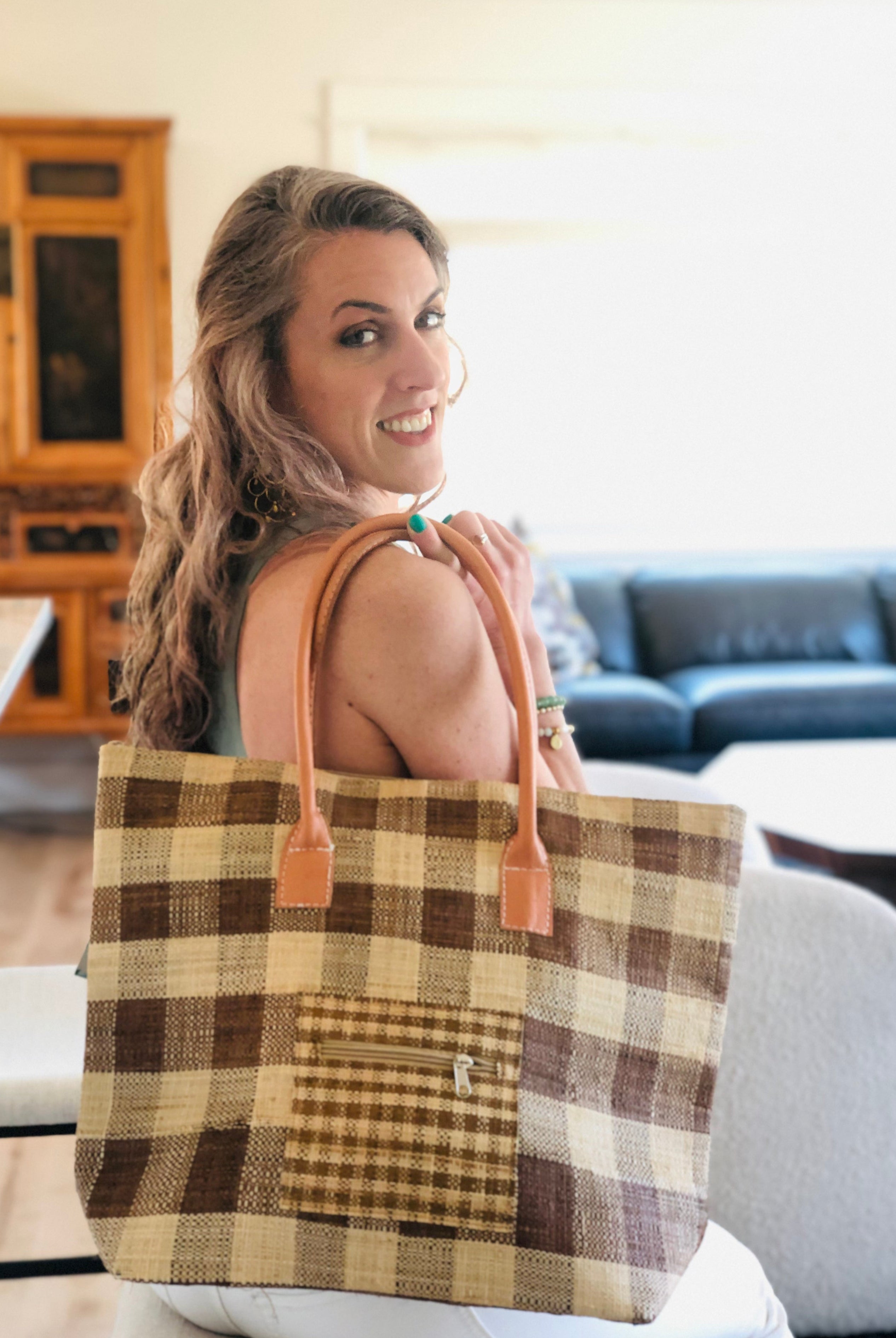 Model wearing Nador Gingham Zippered Straw Bag in two tone cinnamon/tobacco/brown and natural straw color plaid pattern handbag handmade from loomed raffia palm shopping tote that packs flat with zipper closure and leather handles beach bag purse - Shebobo