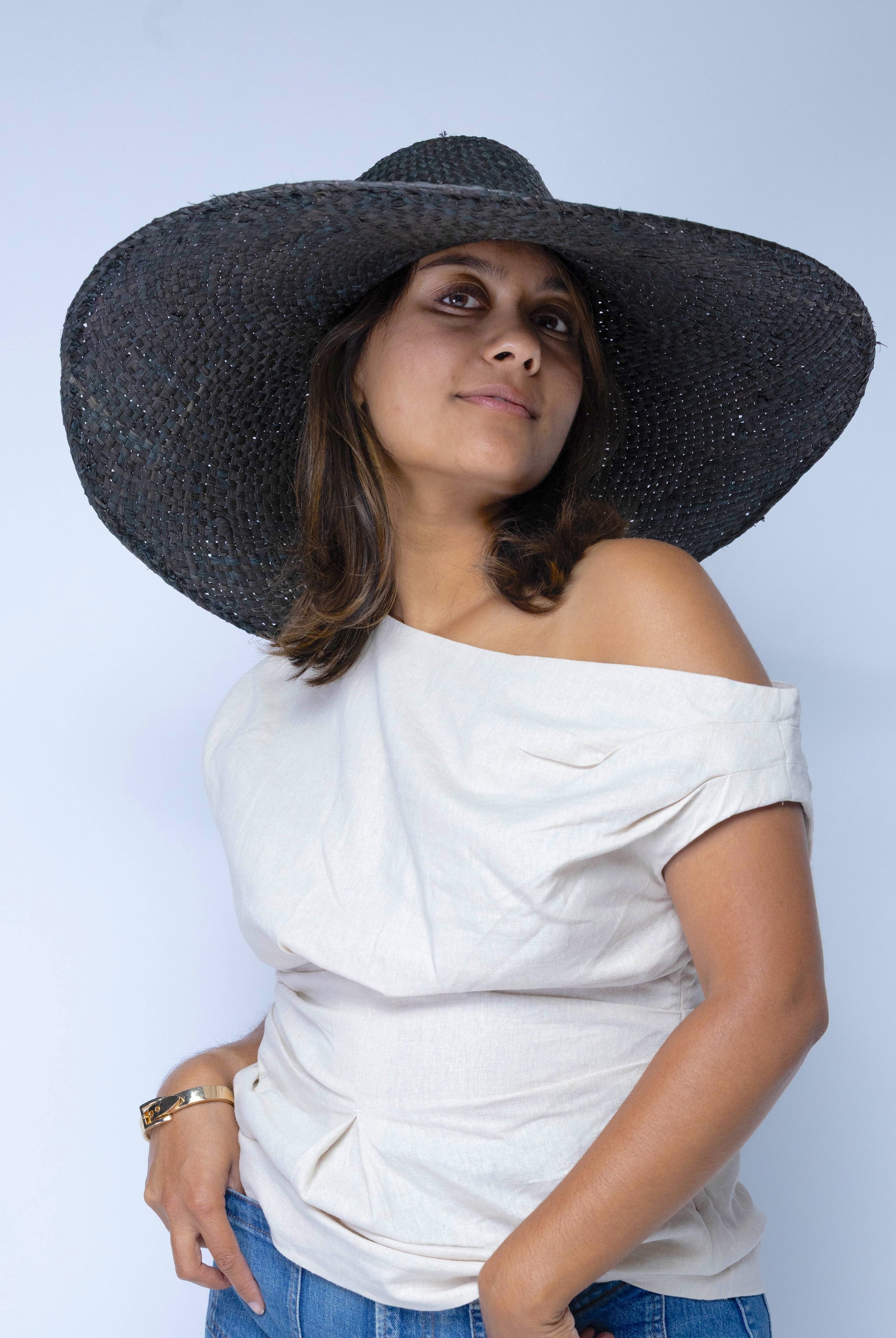 Model wearing 7" Wide Brim Natasha Black Woven XL Straw Sun Hat handmade woven natural raffia palm fiber in a solid hue of black with matching adjustable twisted raffia hat band and and extra wide brim - Shebobo