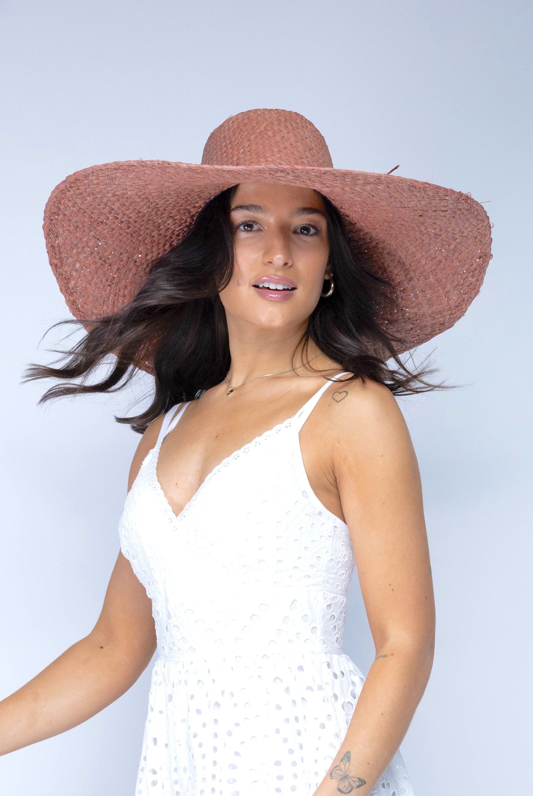 Model wearing 7" Brim Natasha Blush Woven XL Straw Sun Hat handmade woven natural raffia palm fiber in a solid hue of blush red/pink with matching adjustable twisted raffia hat band and and extra wide brim - Shebobo