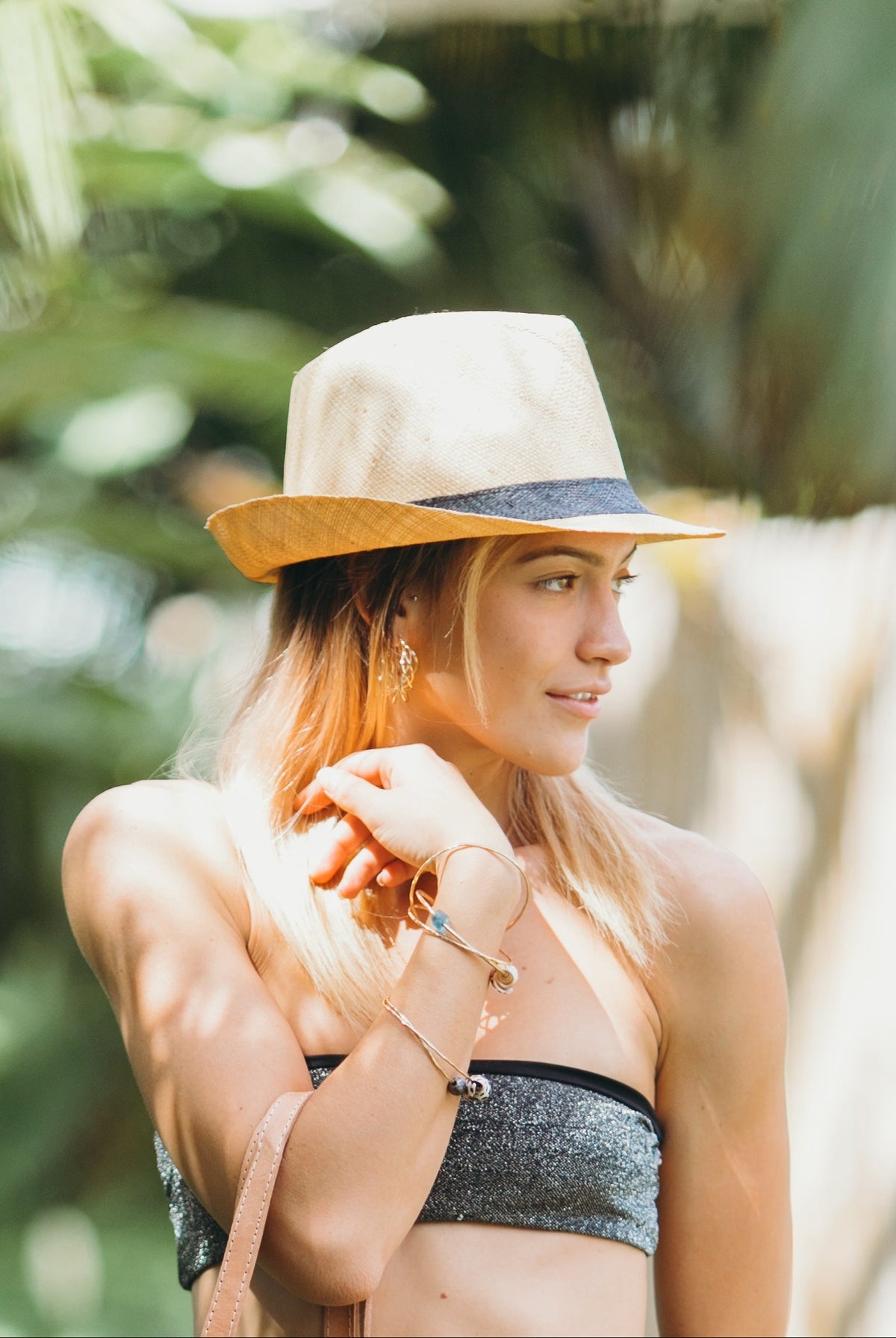 Model wearing Fedra Natural with Black Hat Band - Unisex Fedora Straw Hat handmade loomed natural raffia palm fiber in a solid hue of natural straw color with an attached black hat band - Shebobo