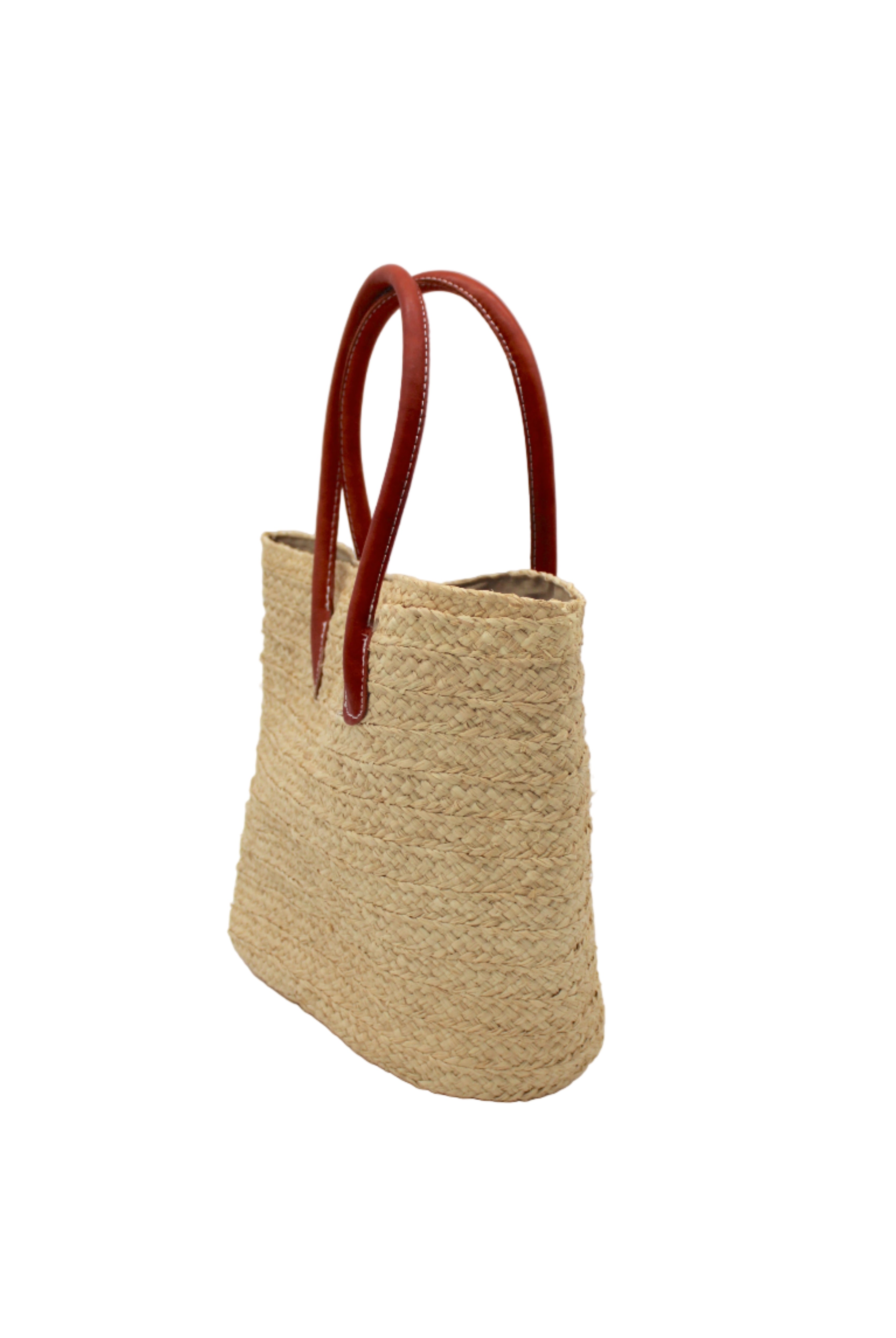 Side view Nomena Braided Straw Basket Handbag handmade braided natural raffia palm fiber in a solid hue of natural straw color woven into concentric horizontal bands of subtle texture spiraling around the bag with leather handles beach bag shoulder bag purse - Shebobo