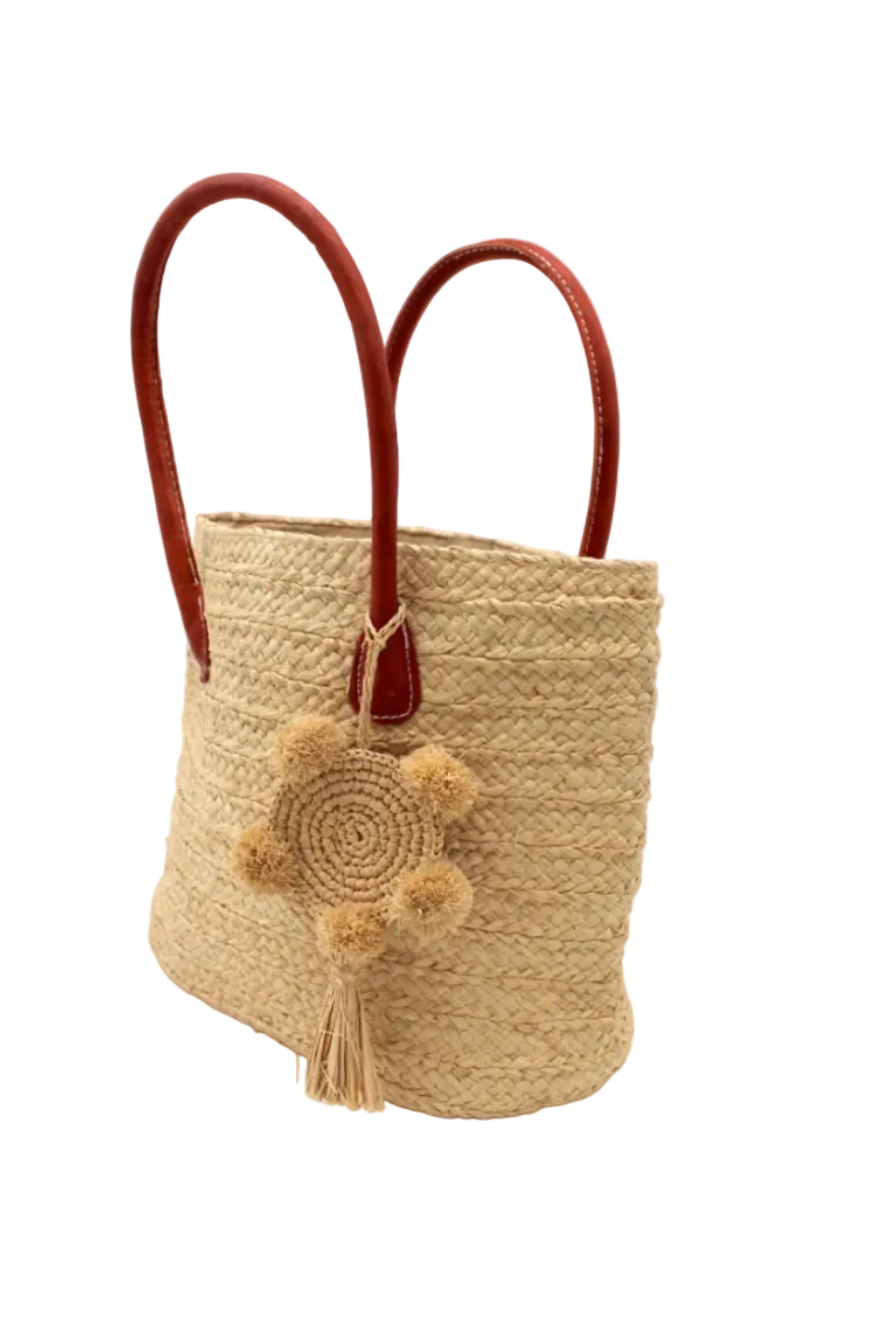 Side view Nomena Braided Straw Basket Handbag handmade braided natural raffia palm fiber in a solid hue of natural straw color woven into concentric horizontal bands of subtle texture spiraling around the bag with leather handles beach bag shoulder bag purse with matching crochet dreamcatcher pompom and tassel charm embellishment - Shebobo