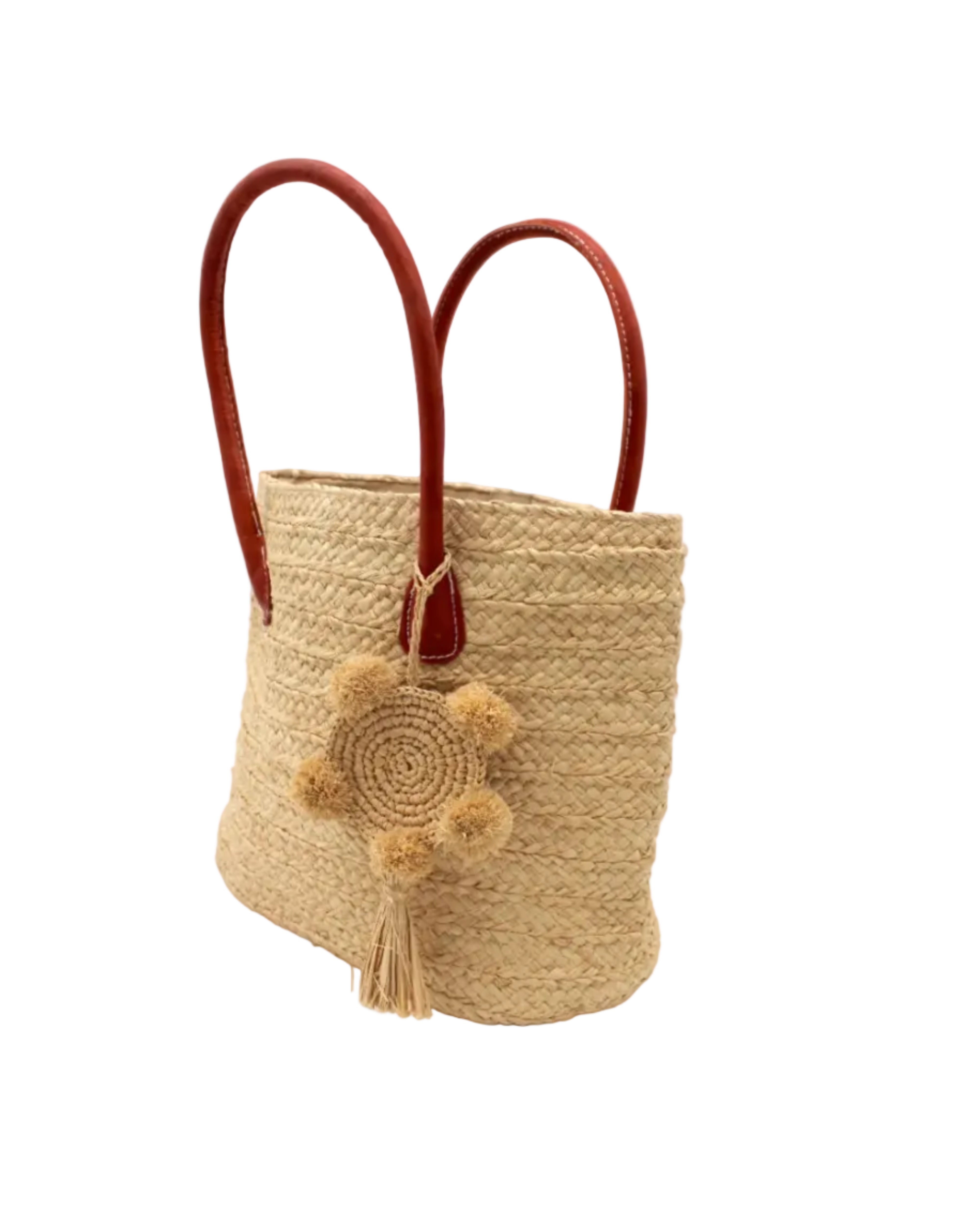 Side view Nomena Braided Straw Basket Handbag handmade braided natural raffia palm fiber in a solid hue of natural straw color woven into concentric horizontal bands of subtle texture spiraling around the bag with leather handles beach bag shoulder bag purse with matching crochet dreamcatcher pompom and tassel charm embellishment - Shebobo
