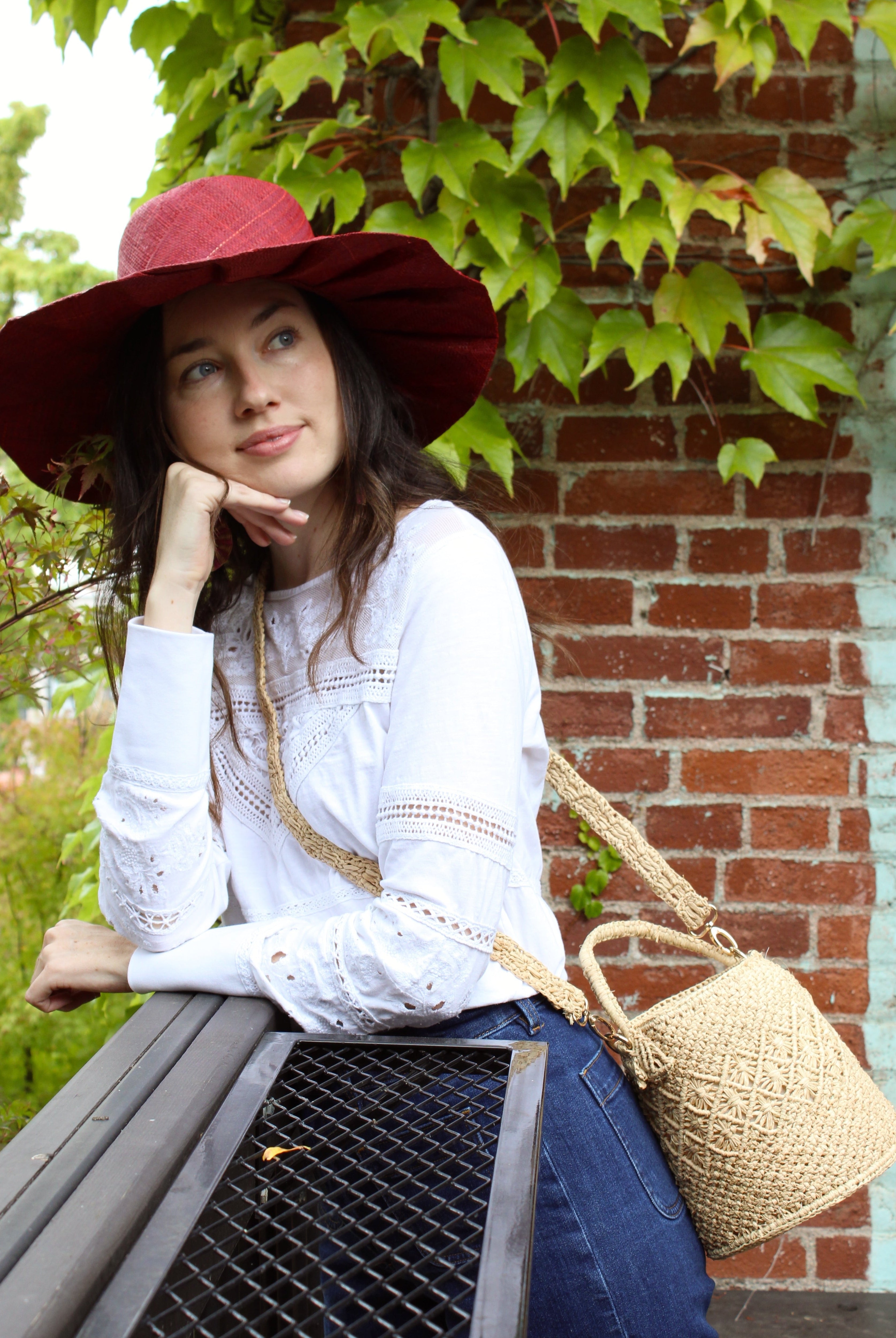Model wearing Paloma Macrame Diamond & Crochet Straw Bucket Handbag Convertible Crossbody Bag handmade natural raffia palm fiber macrame and crochet in a solid hue of natural straw color round bottomed bag with three even horizontal bands of texture the top and bottom subtle link pattern and the center geometric diagonal starburst or flower in diamond pattern with detachable shoulder strap - Shebobo (with Lilly 5" Brim Fan Pleated Straw Sun Hats with Big Bow)