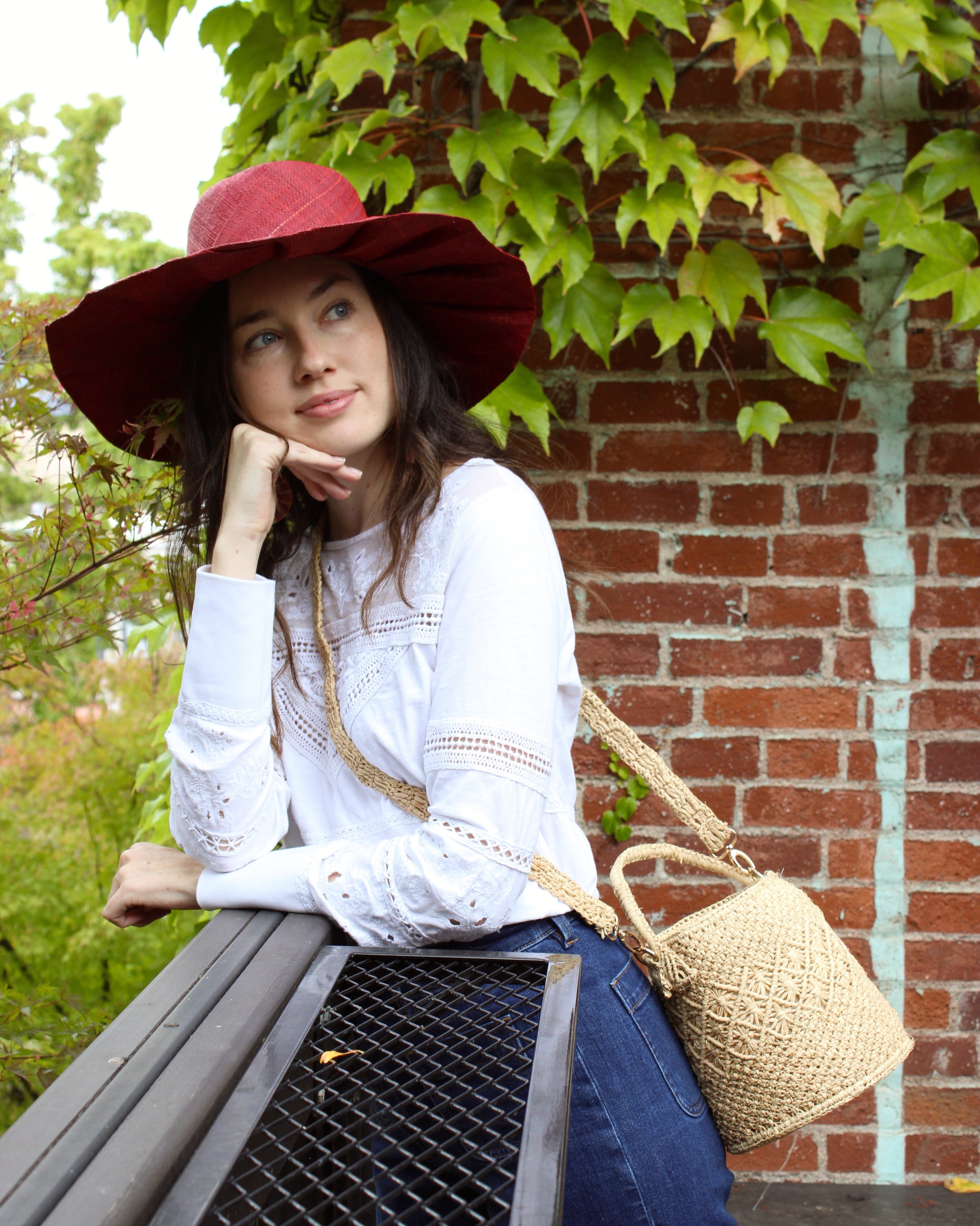 Model wearing Paloma Macrame Diamond & Crochet Straw Bucket Handbag Convertible Crossbody Bag handmade natural raffia palm fiber macrame and crochet in a solid hue of natural straw color round bottomed bag with three even horizontal bands of texture the top and bottom subtle link pattern and the center geometric diagonal starburst or flower in diamond pattern with detachable shoulder strap - Shebobo (with Lilly 5" Brim Fan Pleated Straw Sun Hats with Big Bow)