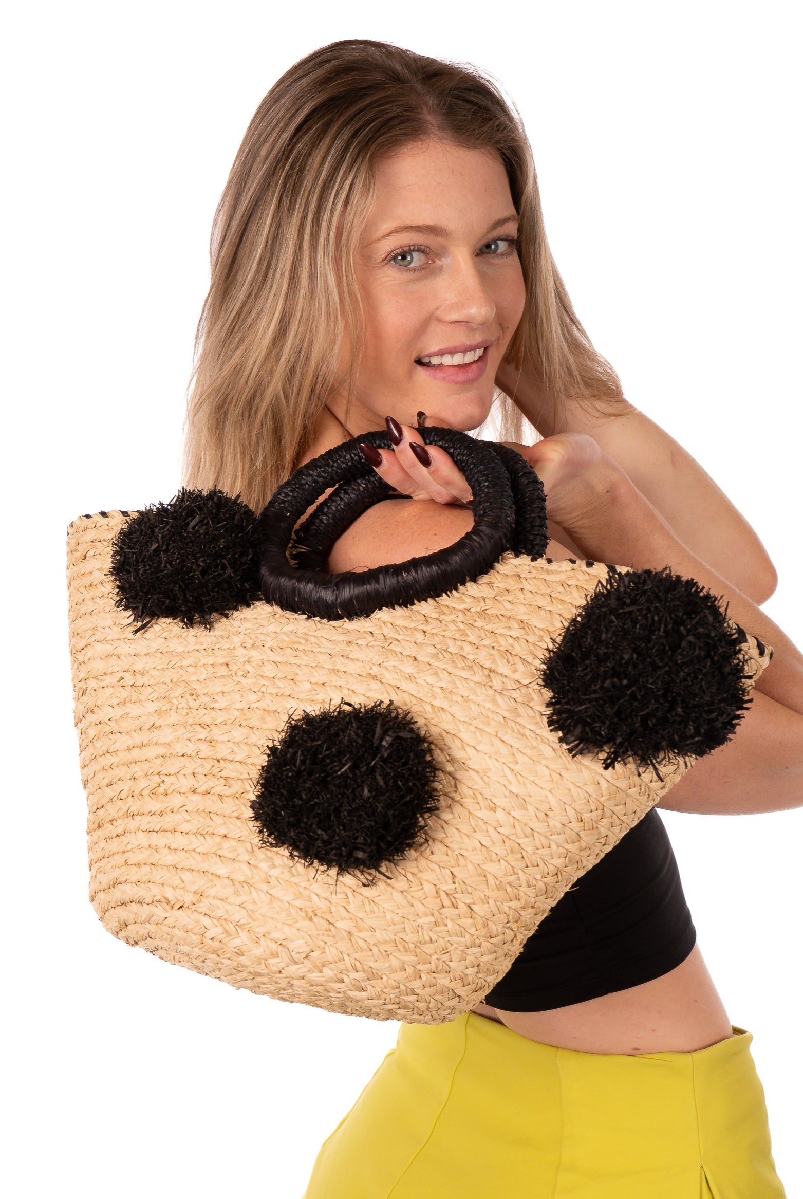 Model wearing Phi Phi Black and Natural Braided Straw Basket with Oversized Raffia Poufs handmade raffia palm fiber braided into a solid hue of natural straw color with three randomly placed black hand-brushed fringe poufs per side for embellishment with matching loop wrap top edging and matching crochet loop/braided handles bag handbag - Shebobo