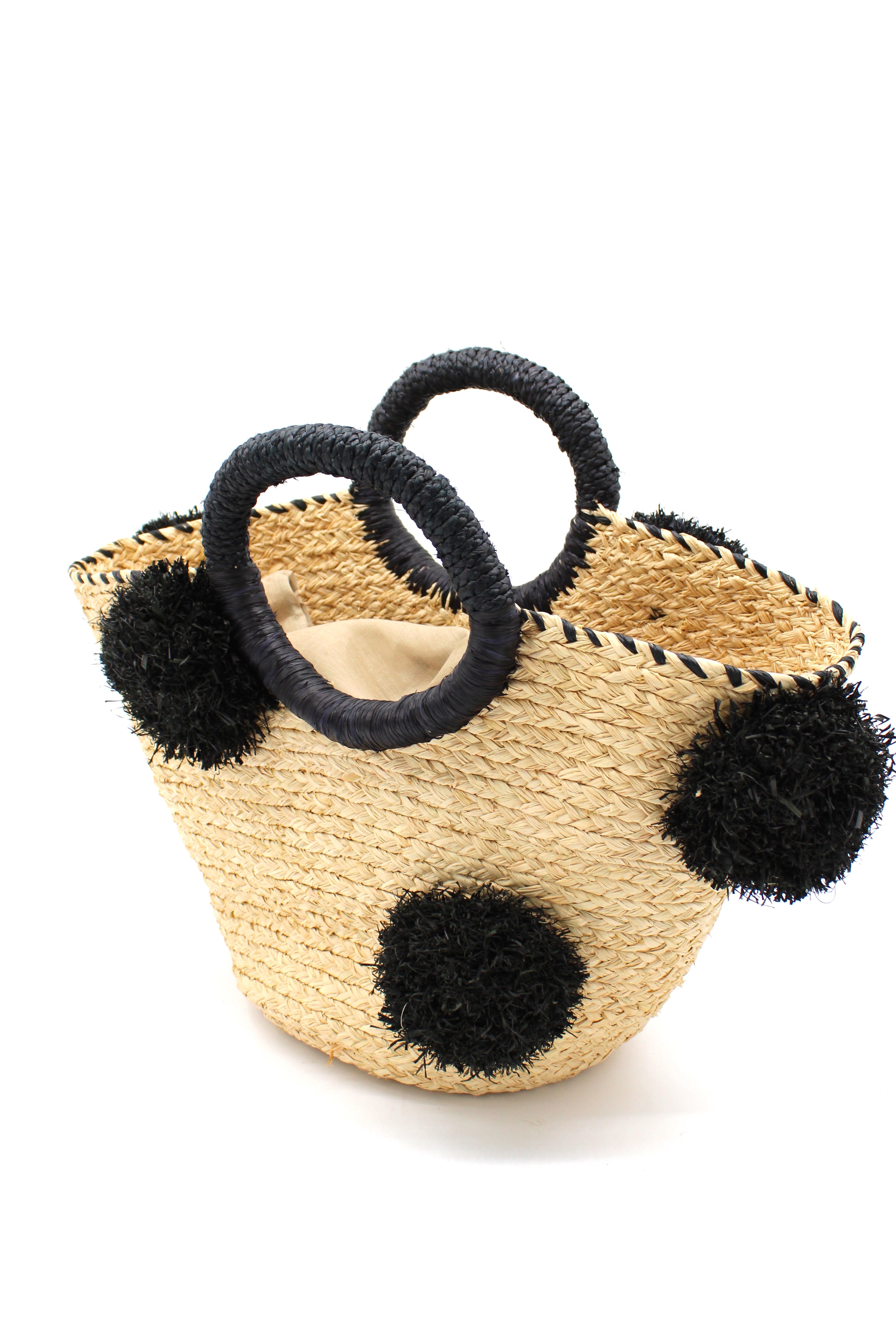 Side View Phi Phi Black and Natural Braided Straw Basket with Oversized Raffia Poufs handmade raffia palm fiber braided into a solid hue of natural straw color with three randomly placed black hand-brushed fringe poufs per side for embellishment with matching loop wrap top edging and matching crochet loop/braided handles bag handbag - Shebobo