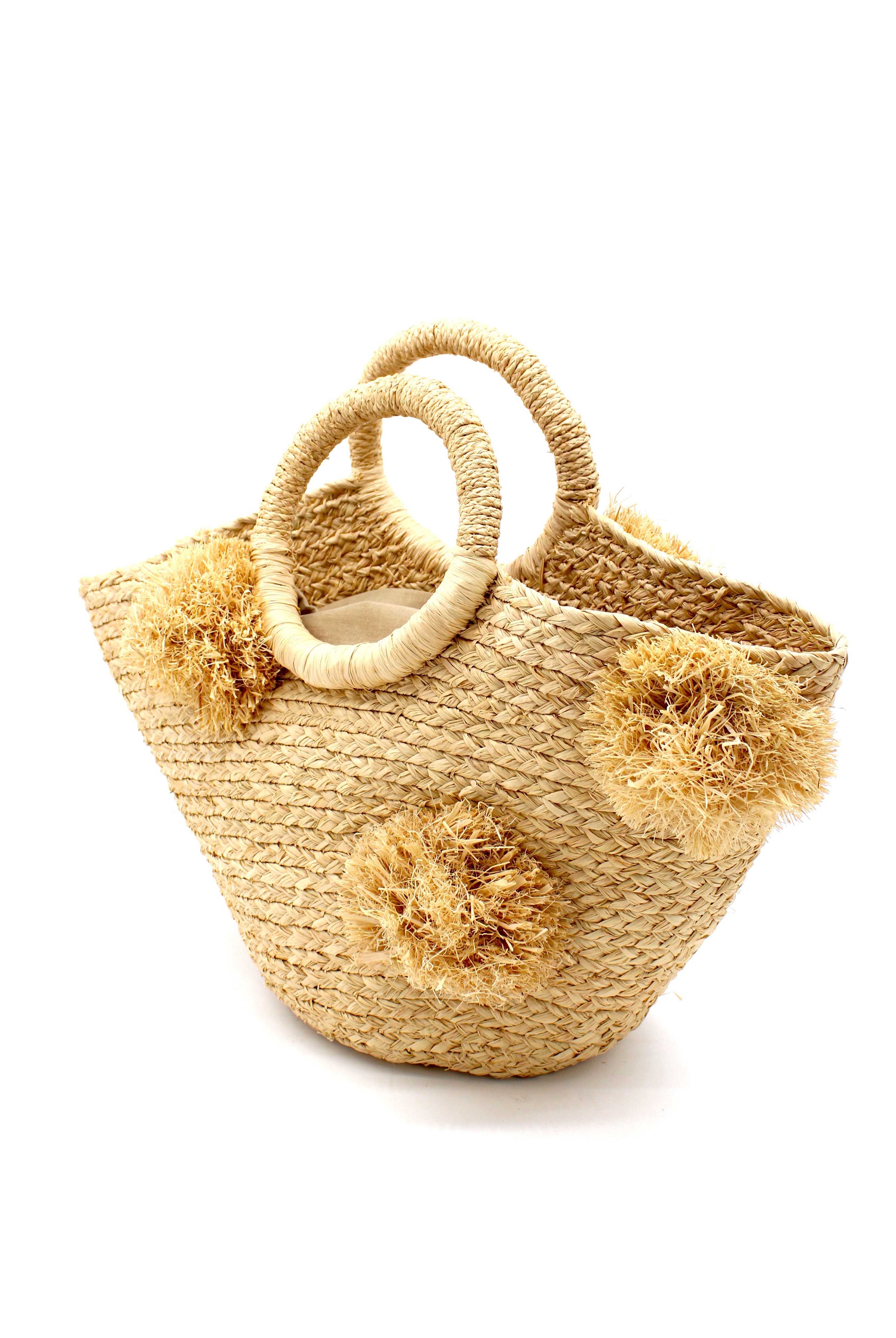 Side View Phi Phi Natural Braided Straw Basket with Oversized Raffia Poufs handmade raffia palm fiber braided into a solid hue of natural straw color with three randomly placed matching hand-brushed fringe poufs per side for embellishment with loop wrap top edging and crochet loop/braided handles bag handbag - Shebobo
