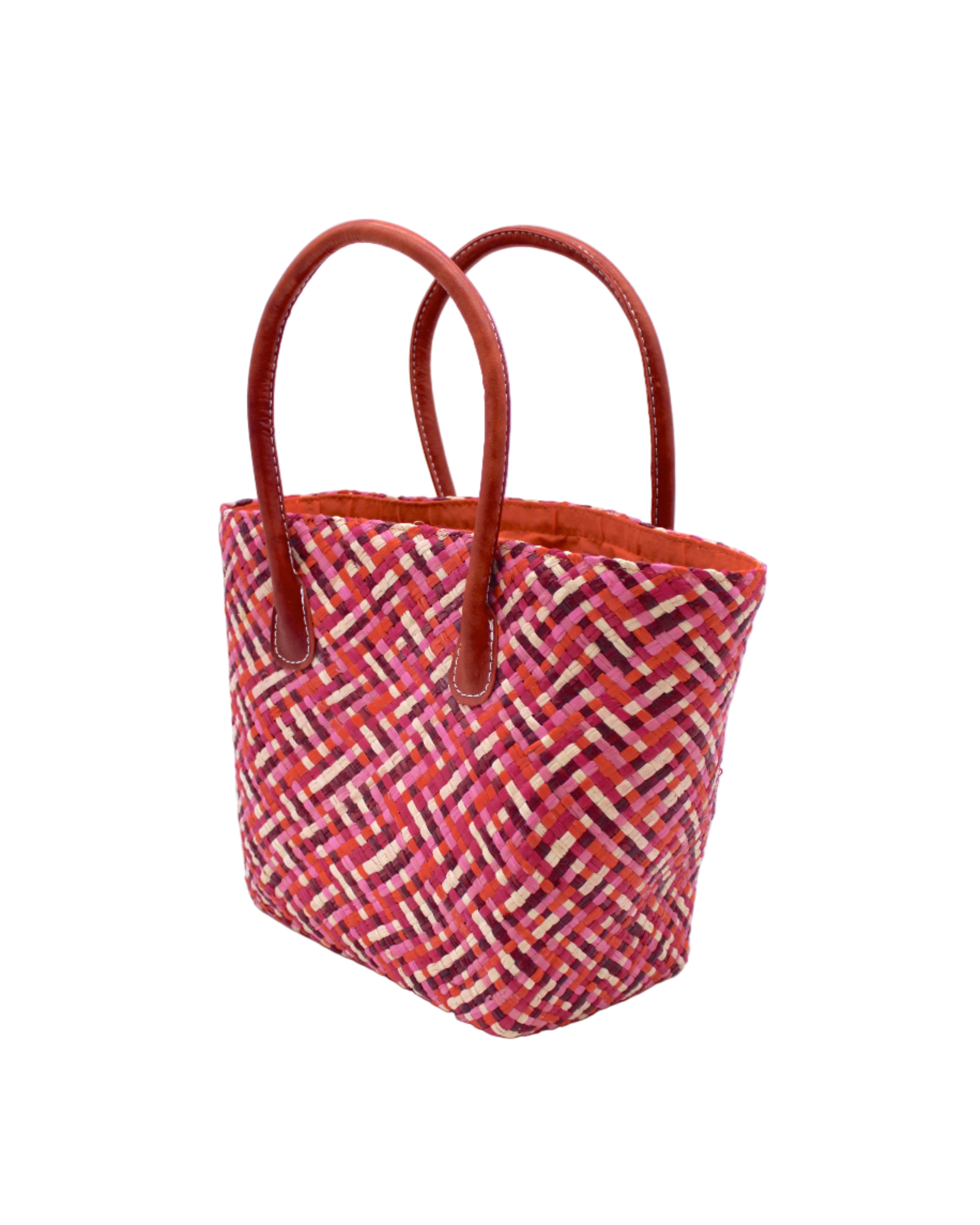 Side view Pianina Passion Multi Small Straw Basket Bag handmade from woven natural raffia palm fiber in a multicolor cross weave pattern of red, light pink, fuchsia, coral, and natural straw color handbag purse with leather handles - Shebobo