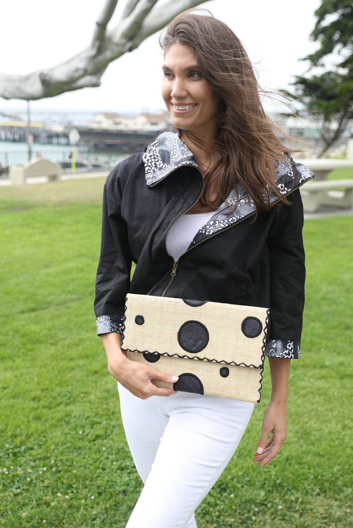 Model wearing Polka Dot Straw Clutch Handbag handmade loomed raffia clutch purse in multisize dot pattern of black dots with matching color cross stitch edging on natural straw color purse- Shebobo