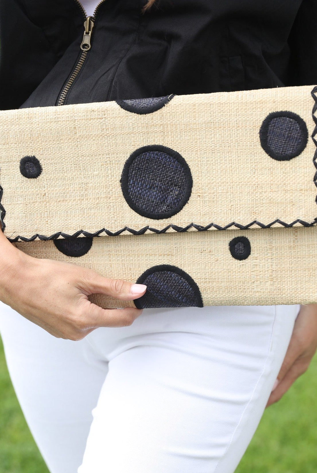 Model wearing Polka Dot Straw Clutch Handbag handmade loomed raffia clutch purse in multisize dot pattern of black dots with matching color cross stitch edging on natural straw color purse- Shebobo