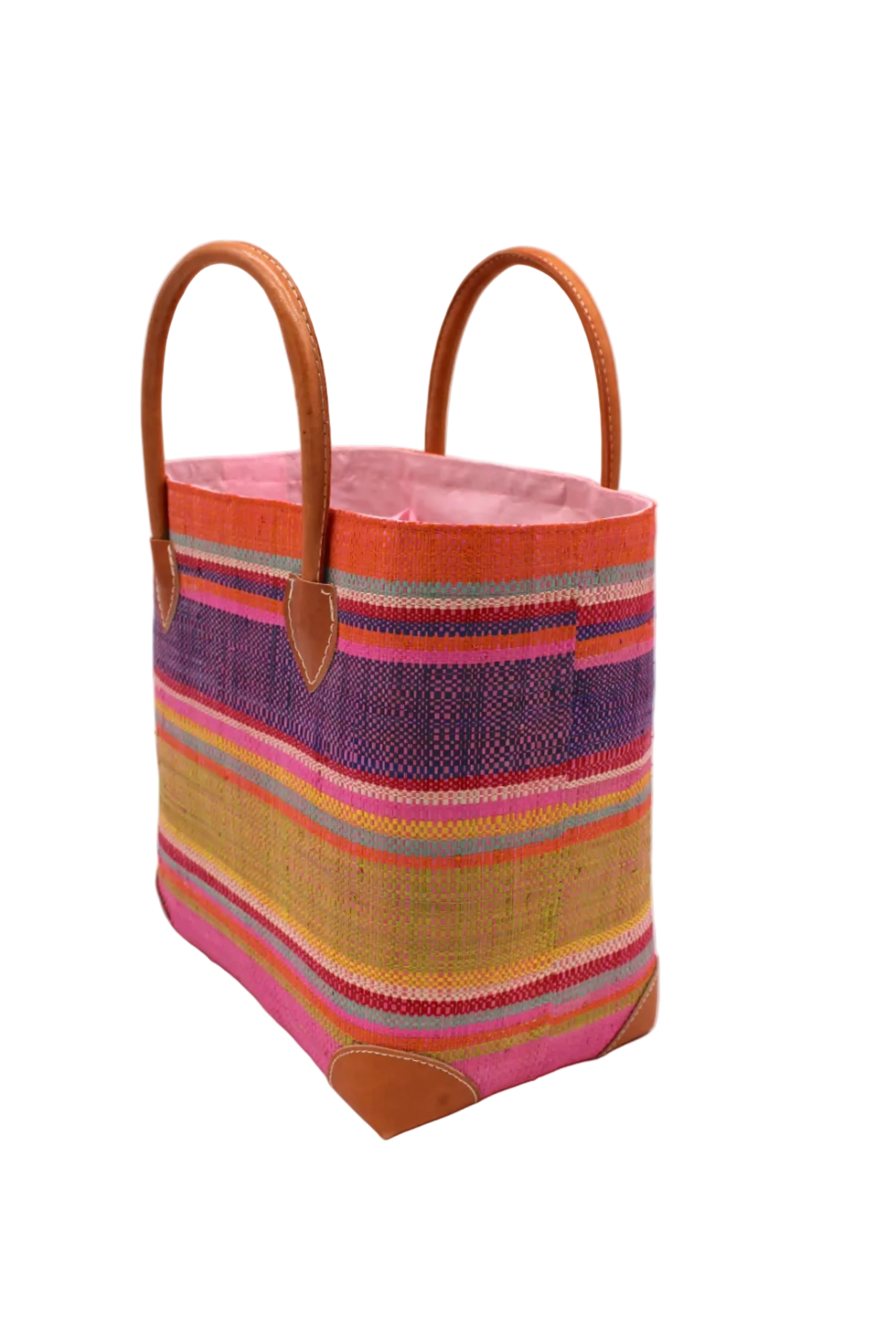 Side view Rayo Stripes Straw Basket Bag Raspberry Swirl handmade loomed natural raffia palm fiber in a multicolor multi width horizontal stripe pattern of coral orange, red, purple, midori lime/green, light pink, yellow, blue, and natural straw color, etc. with leather handles and accents tote beach bag - Shebobo